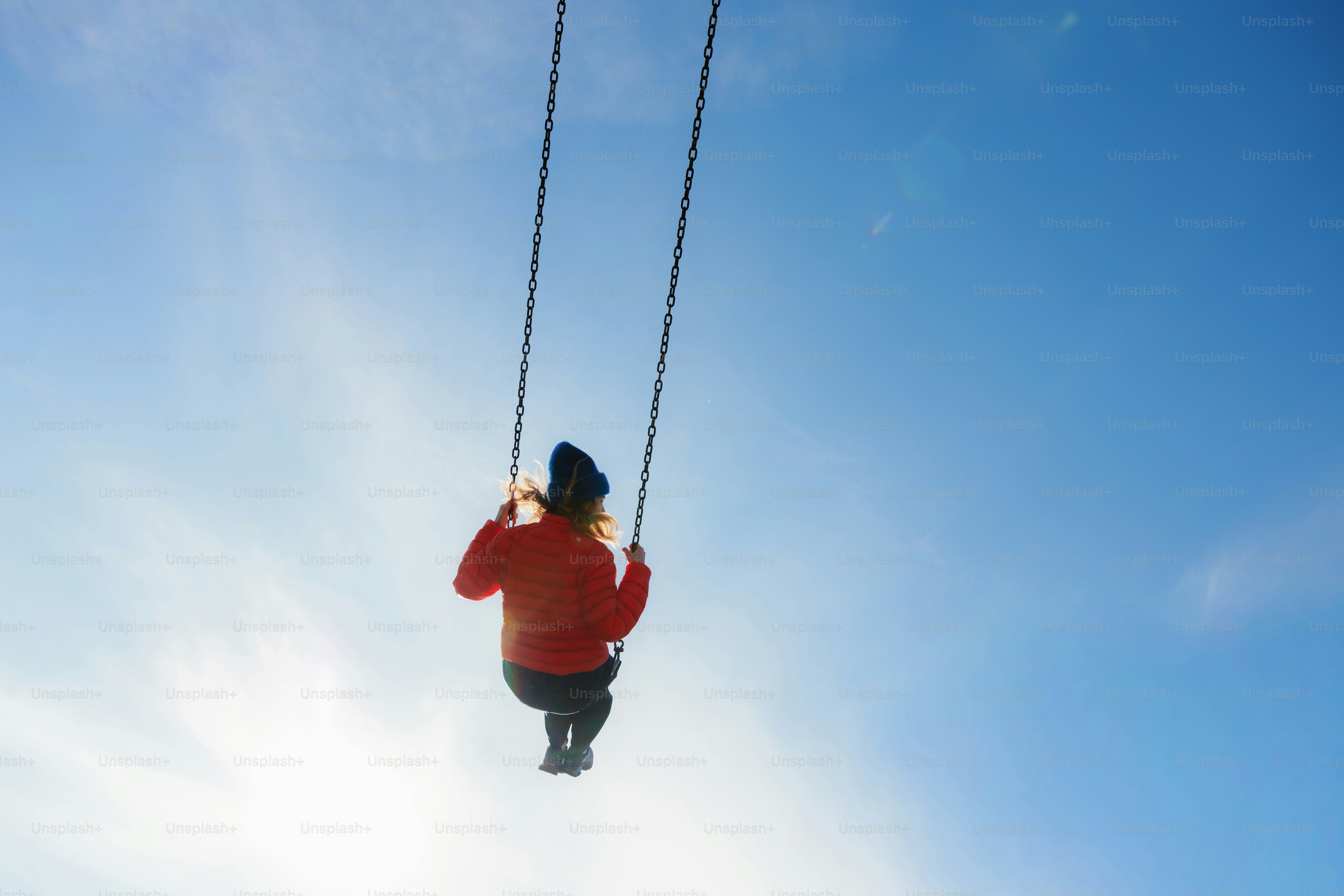 Person swinging high on a swing against blue sky