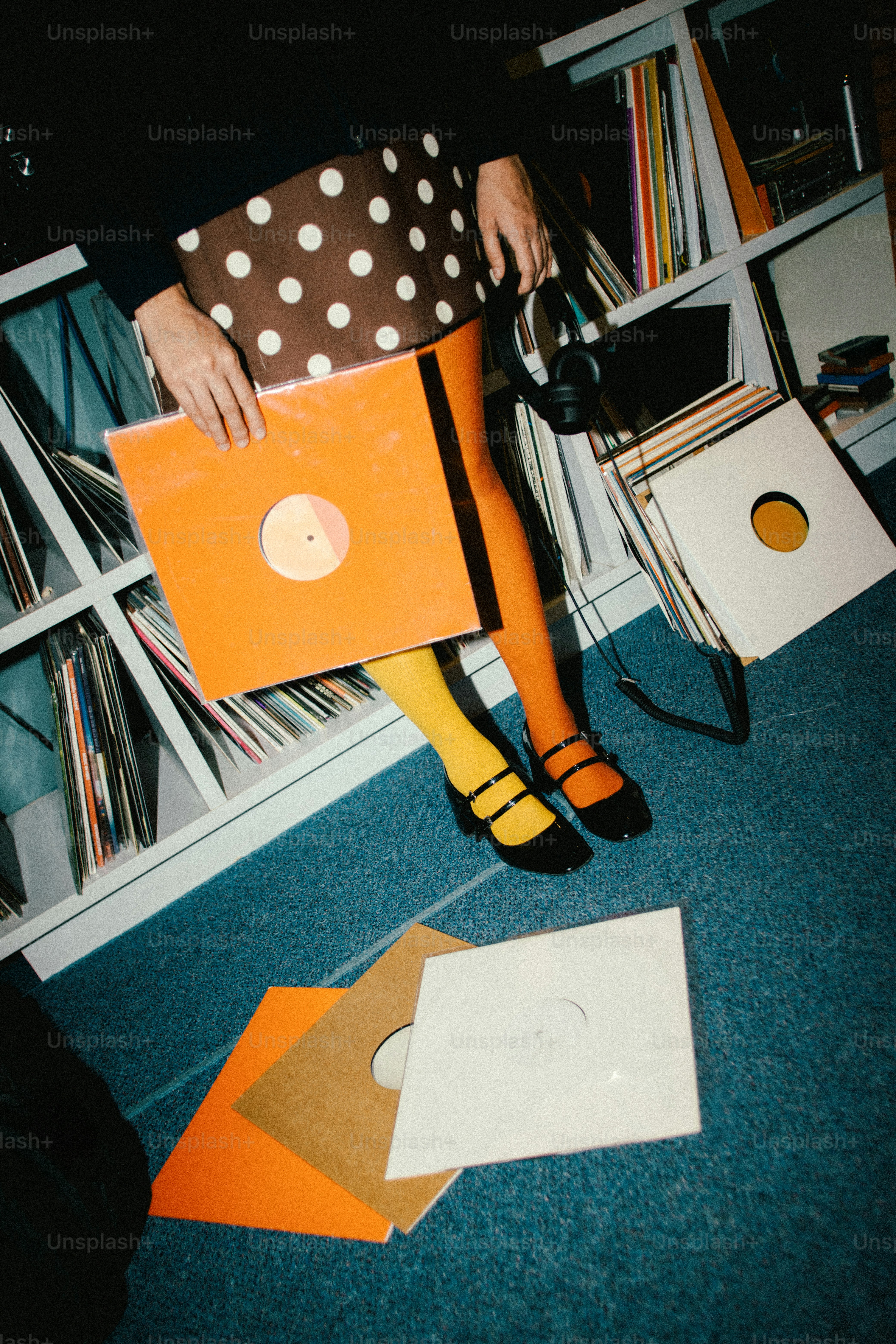 Person holding vinyl records near shelves