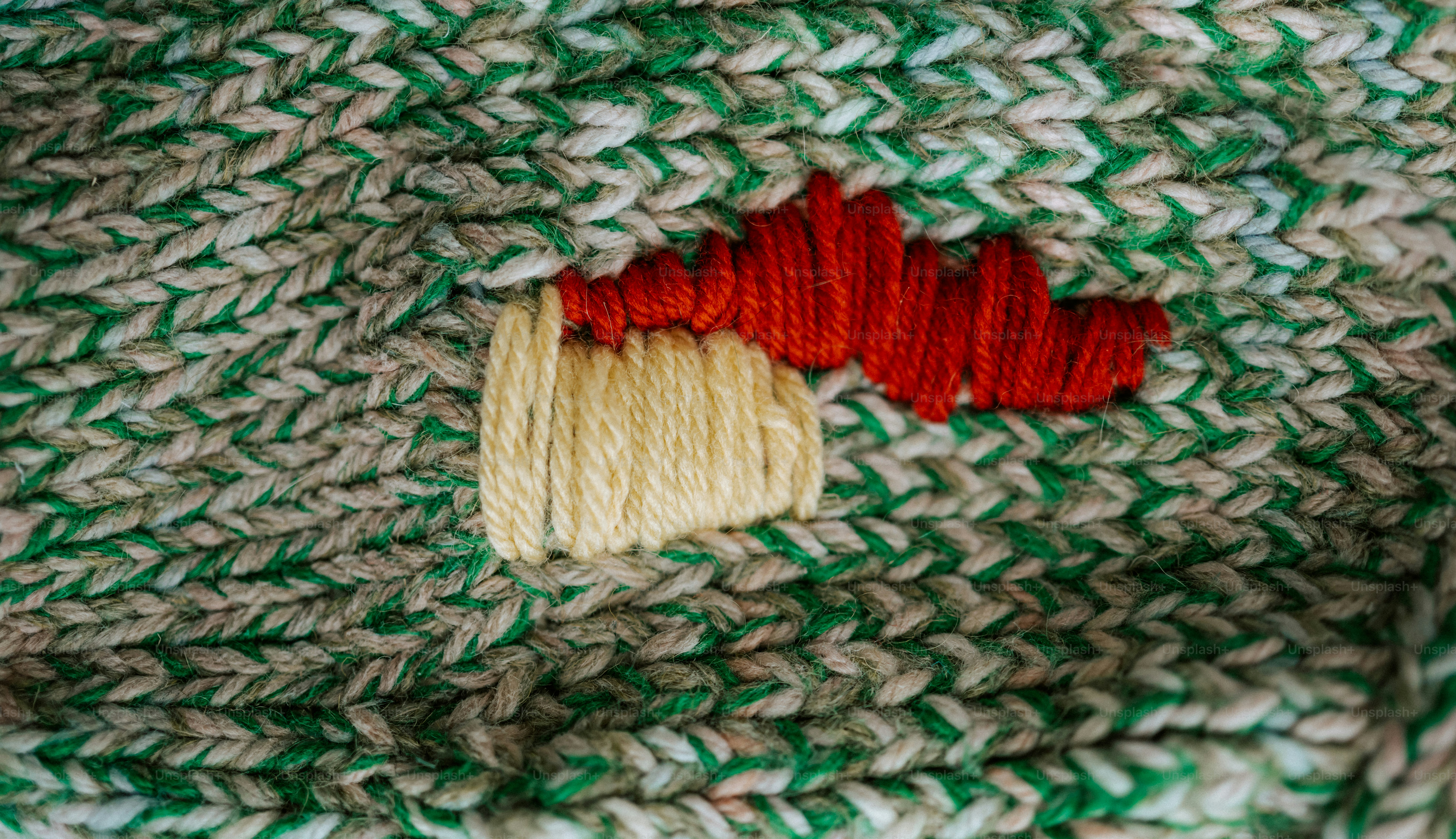 Close-up of a knitted fabric with red and beige embroidery.