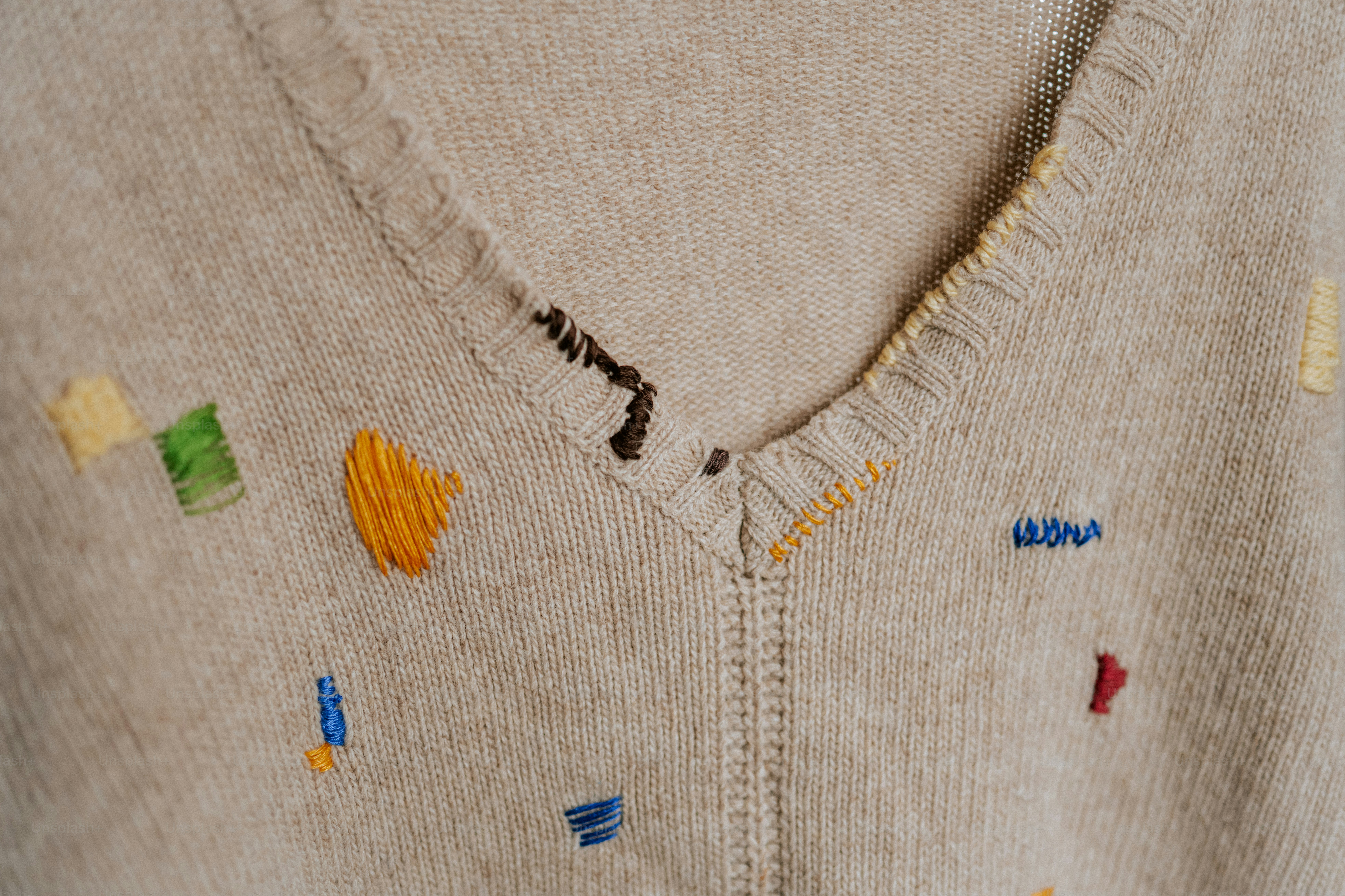 Sweater krem dengan bentuk bordir warna-warni