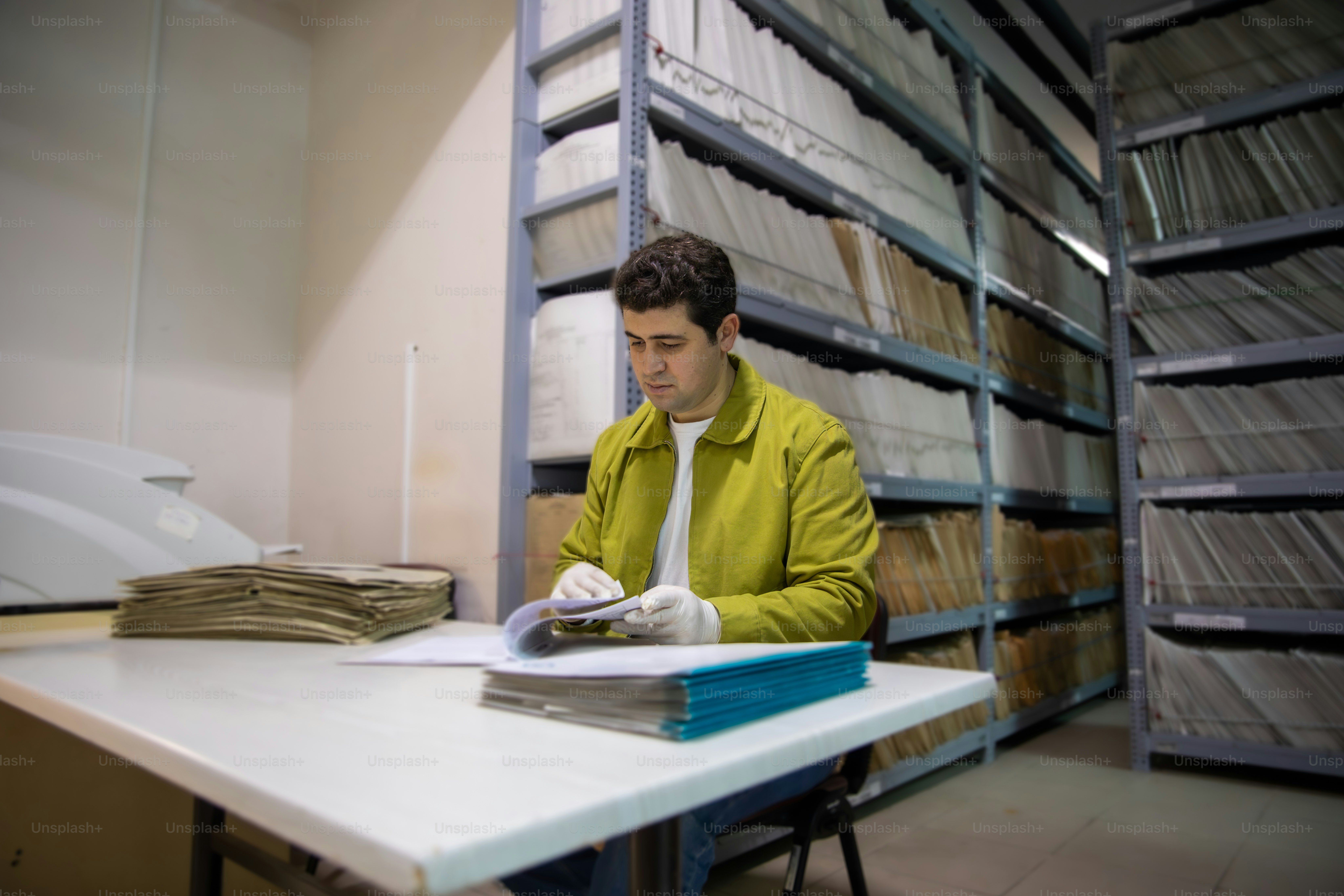 노란 재킷을 입은 남자가 아카이브에서 문서를 검토하고 있다
