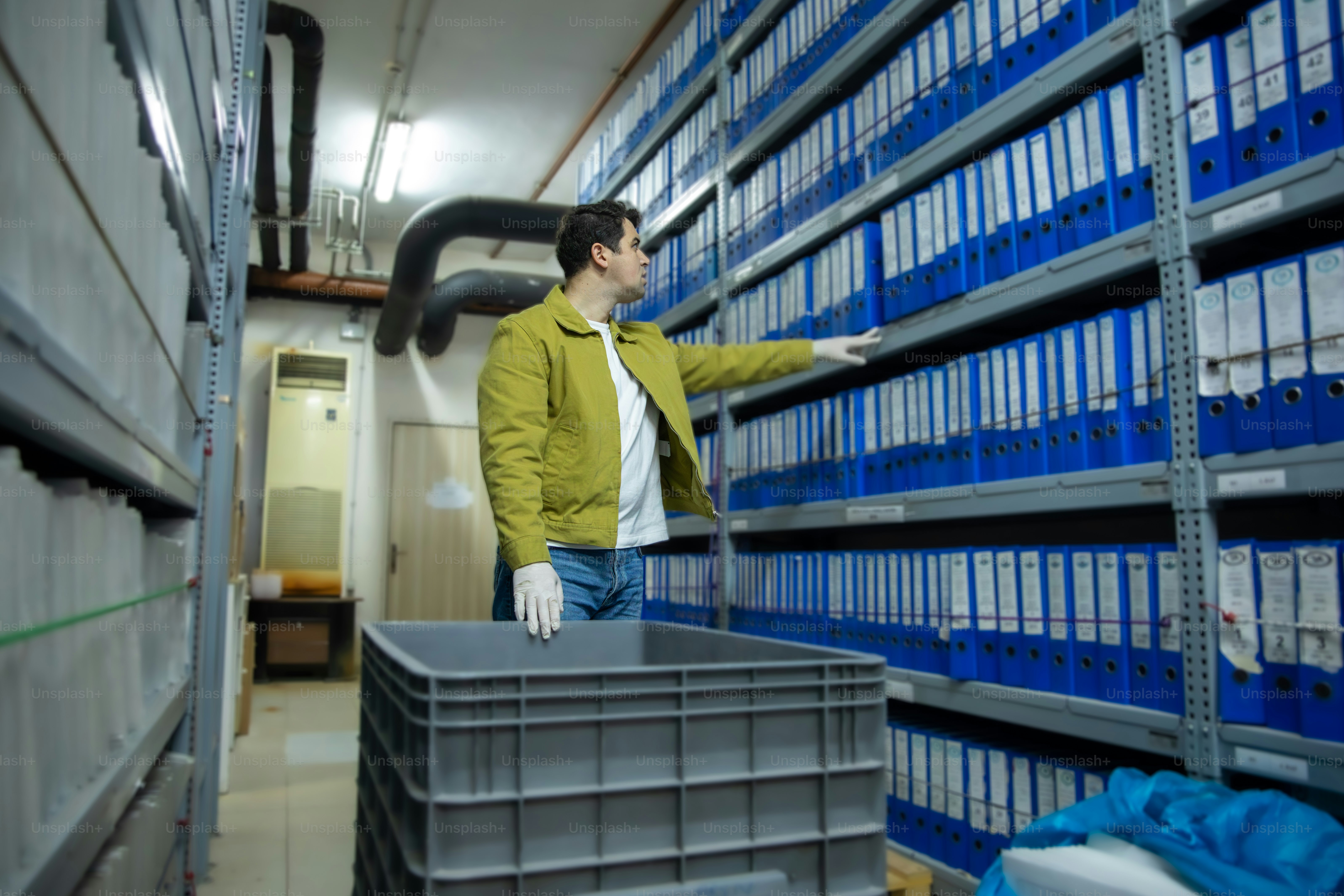 아카이브에서 선반에서 파란색 바인더를 고르는 남자