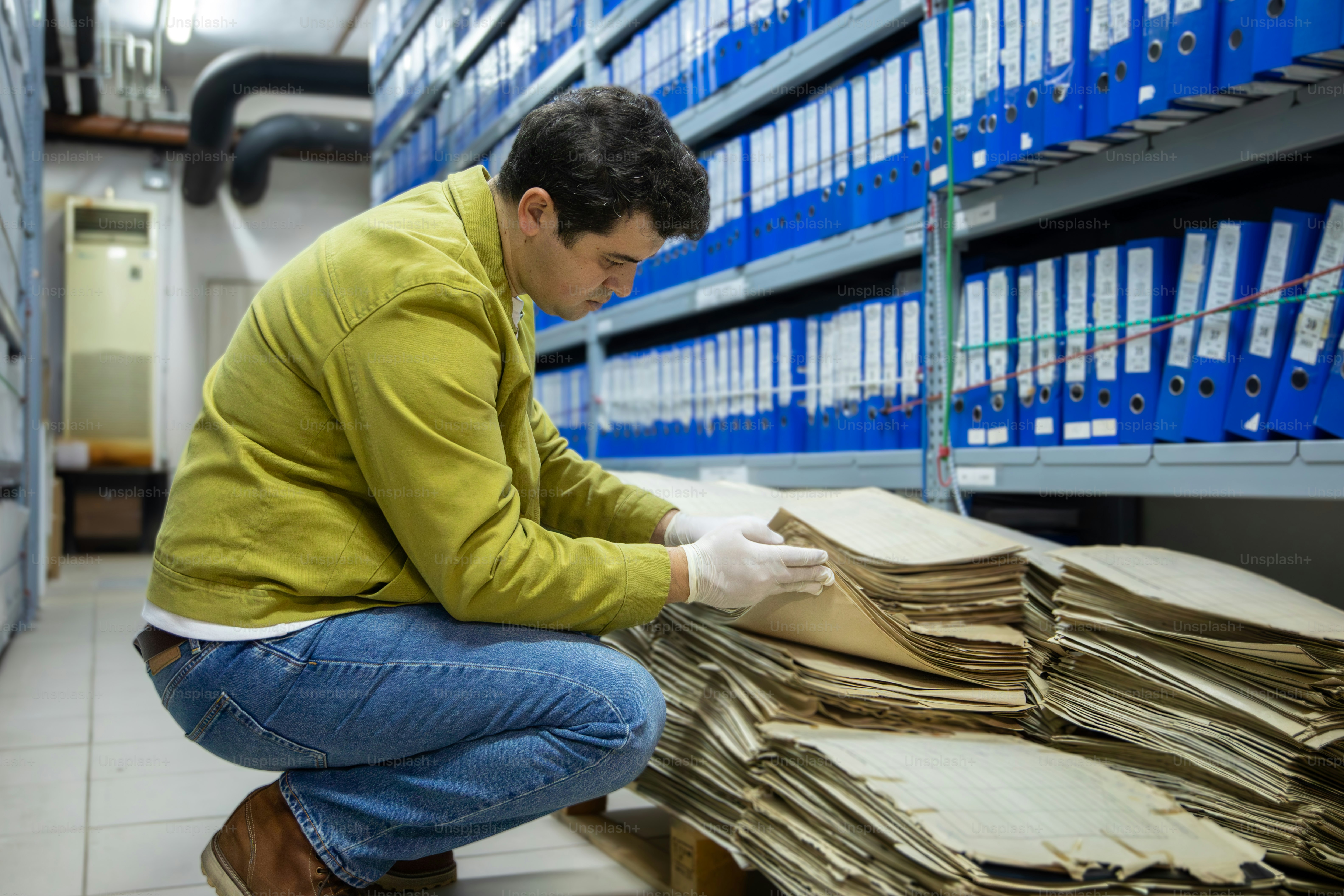 기록실에서 오래된 문서를 들여다보는 남자.