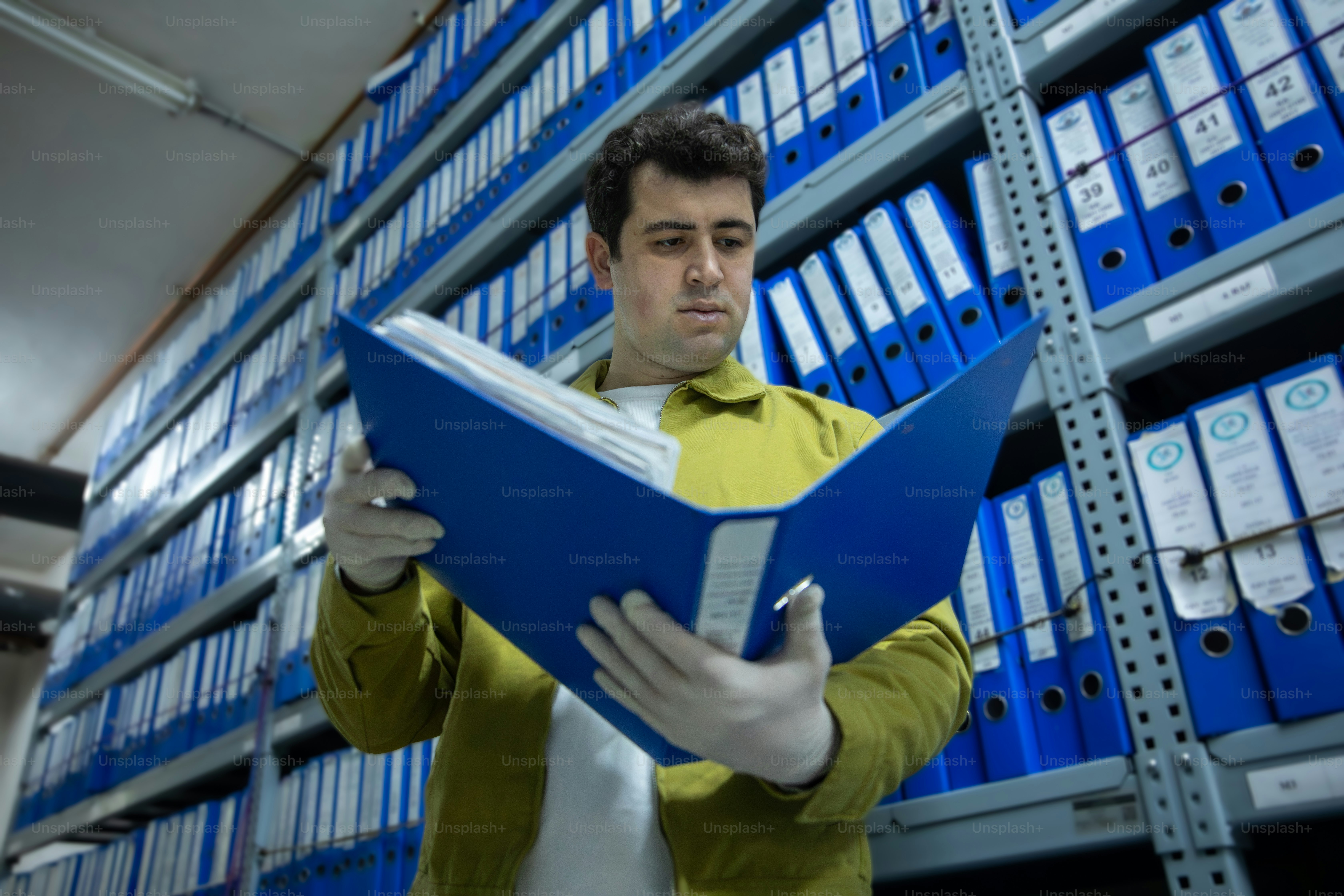 Man looking at a blue folder in archive storage.