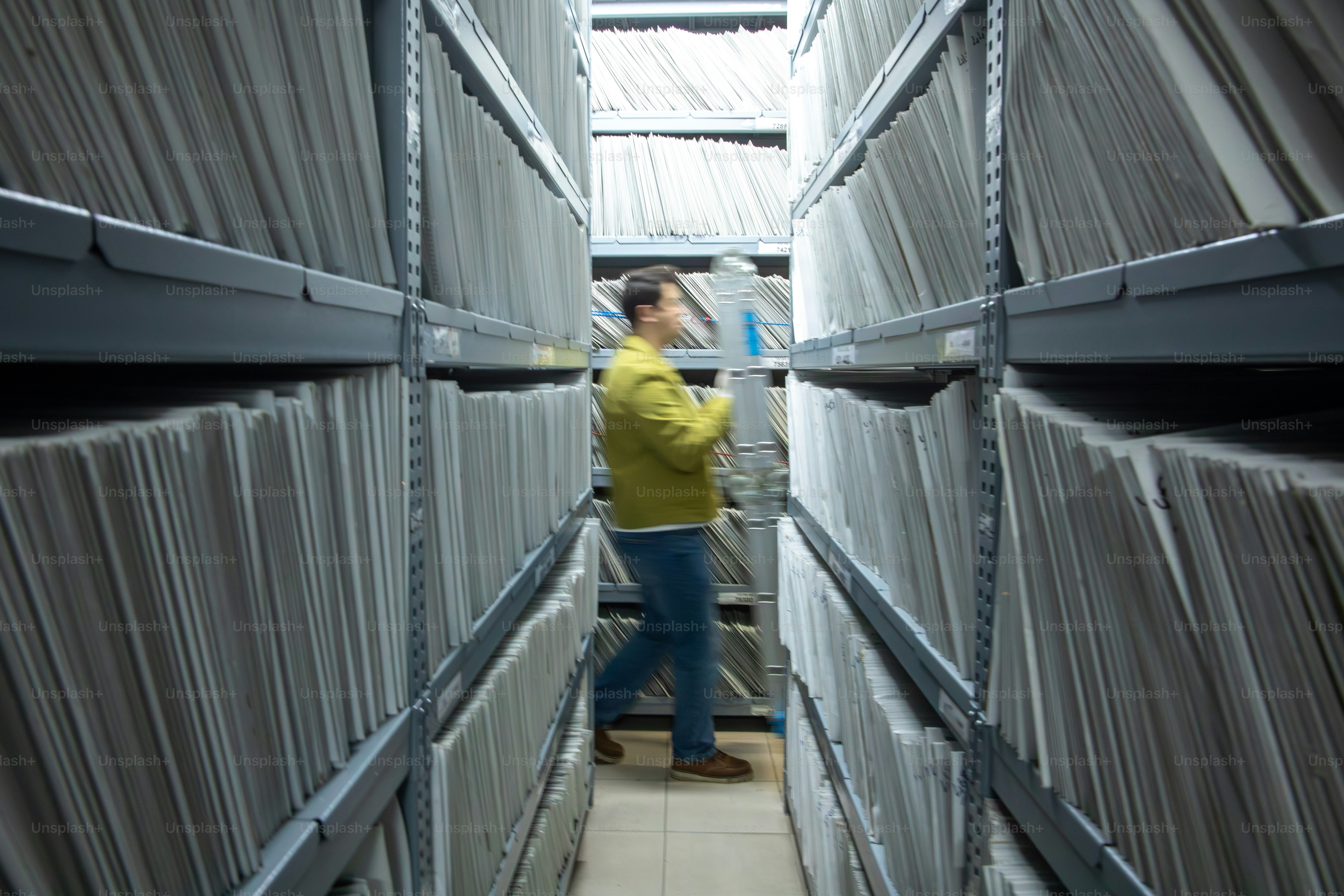 사람이 서류 캐비닛 통로를 걸어 다닌다
