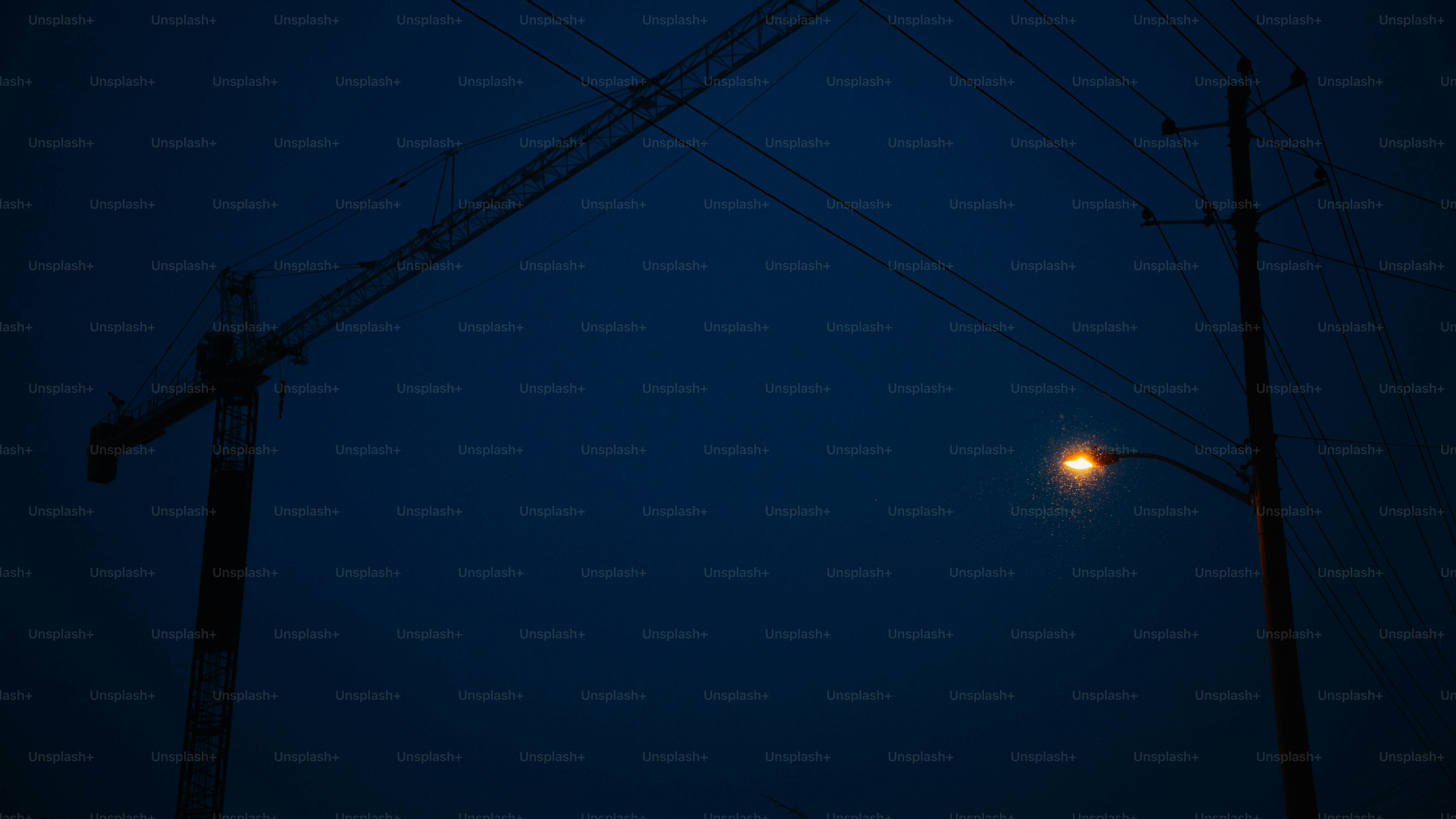 Streetlight illuminates dark blue sky at dusk.