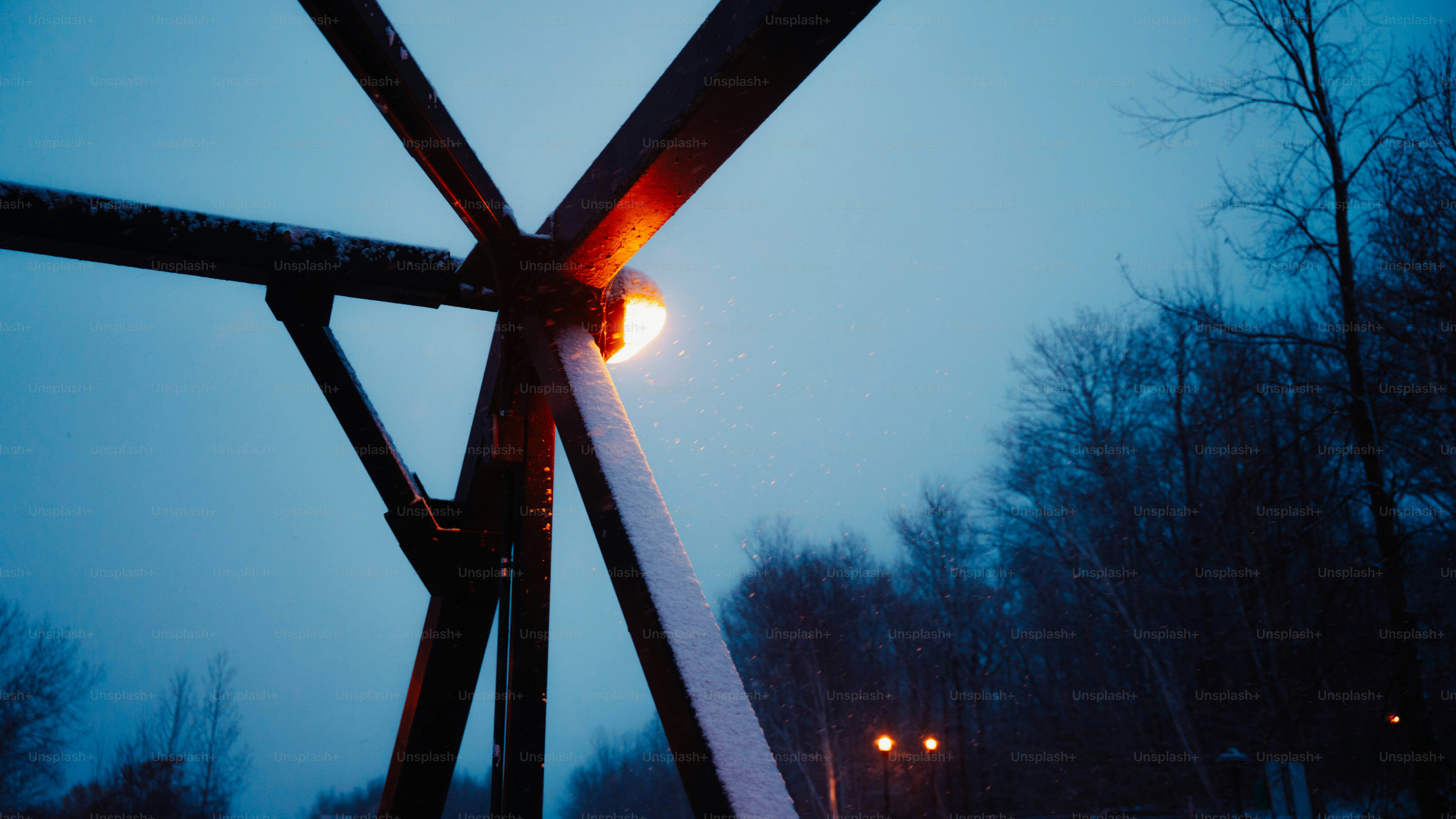 Metal structure with glowing light against twilight sky.