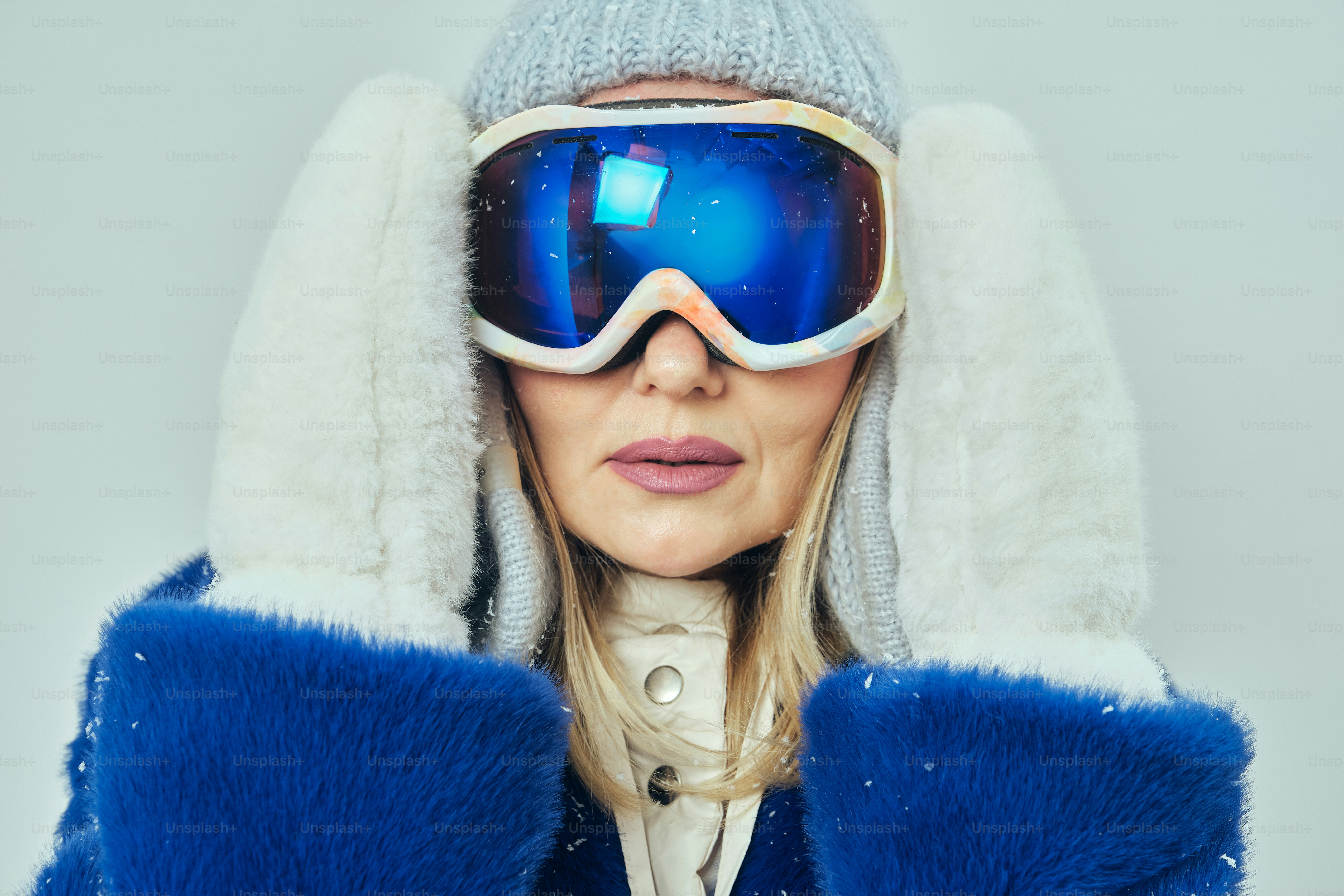 Woman wearing ski goggles and mittens on a gray background photo ...