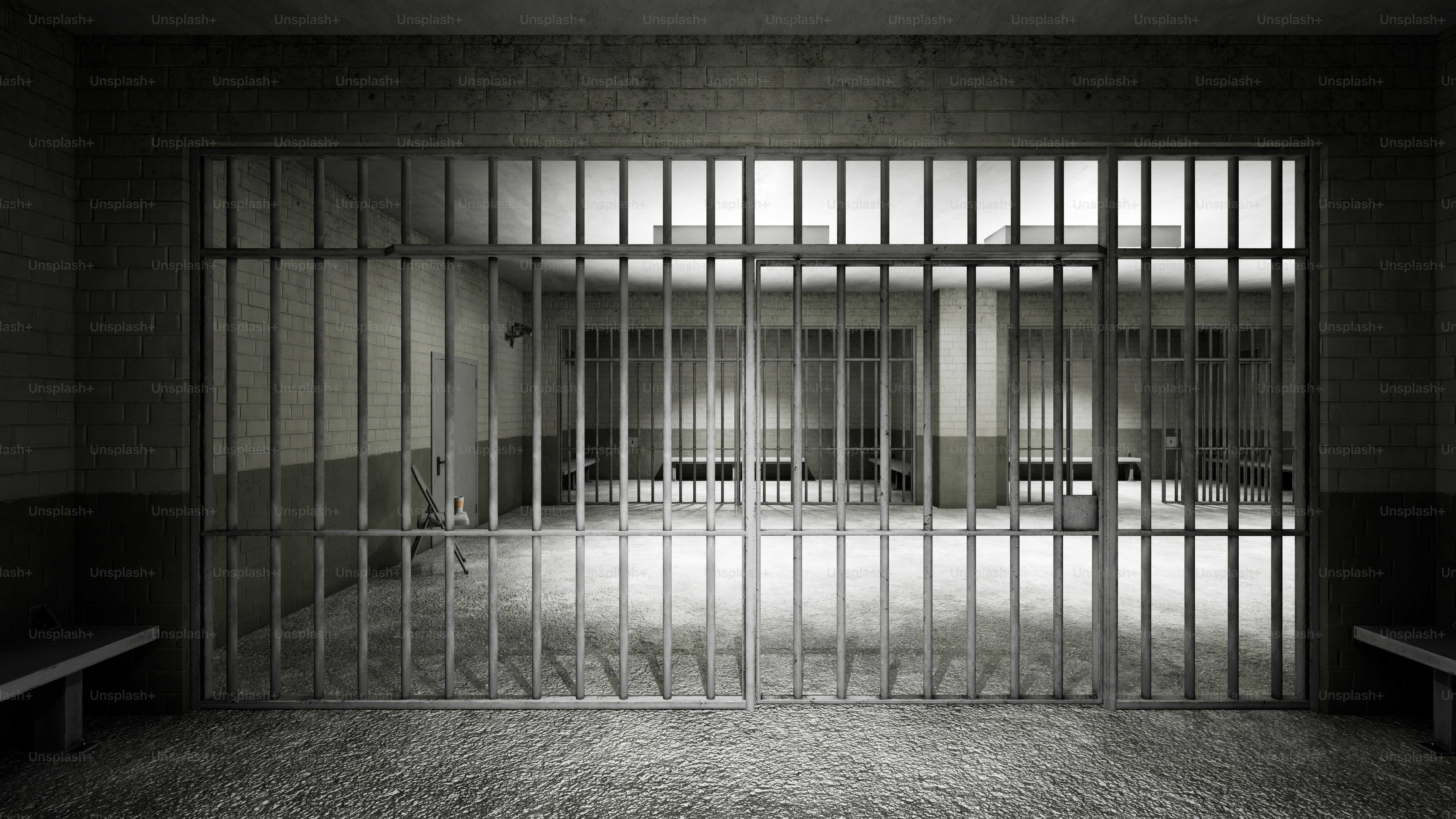 Empty prison cell with metal bars and benches
