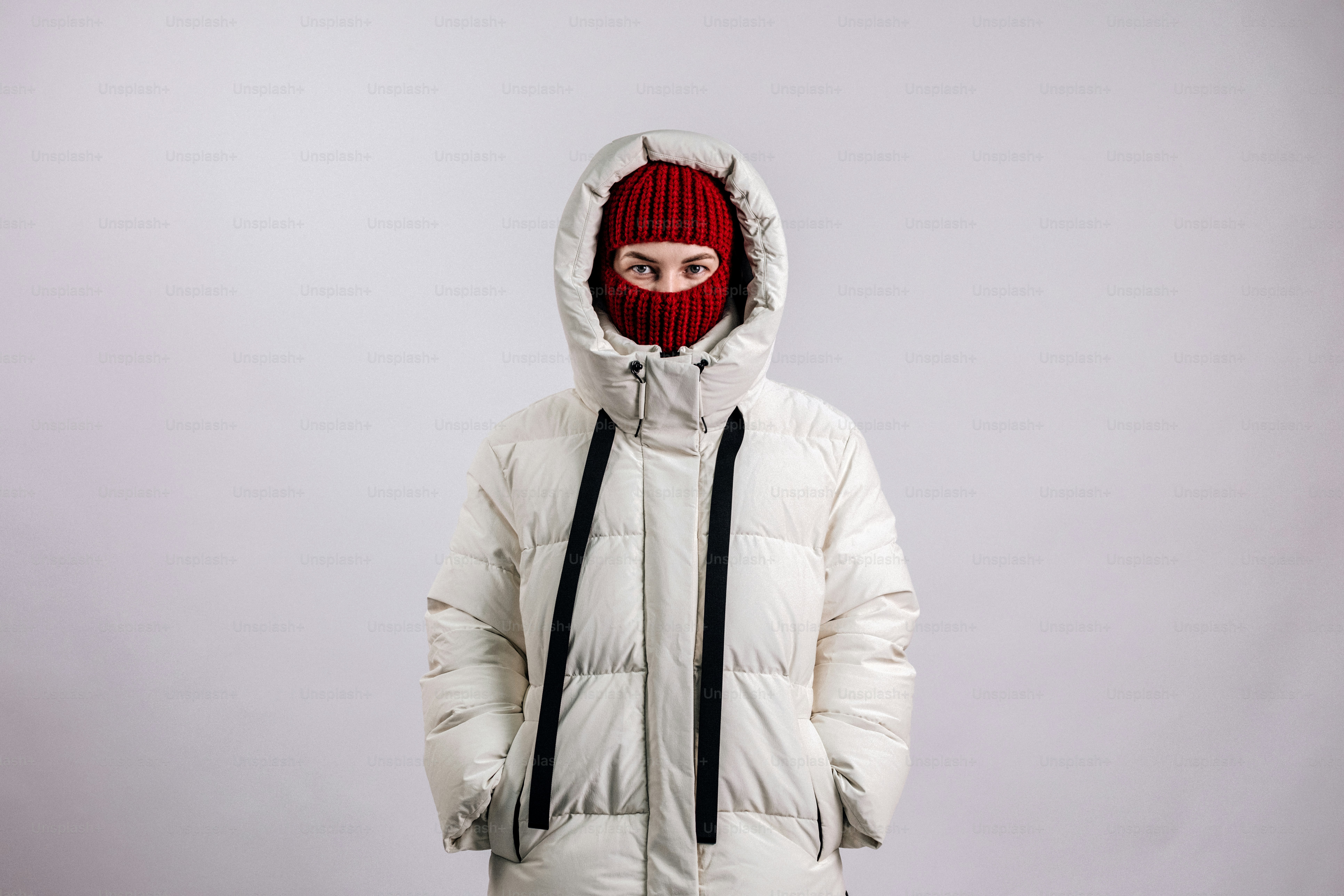 Persona con una chaqueta blanca y pasamontañas roja.