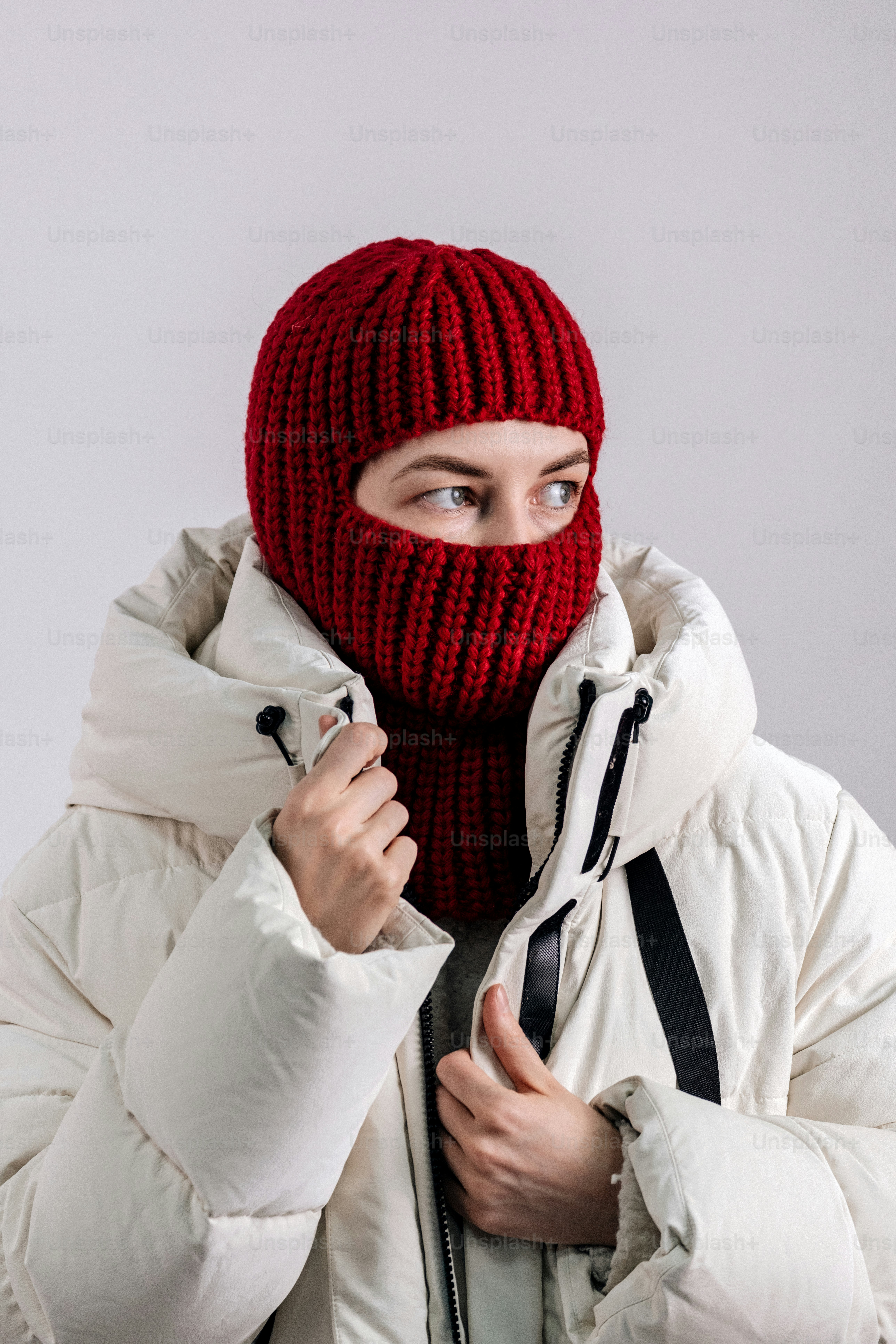 Mujer con pasamontañas de punto rojo y chaqueta blanca