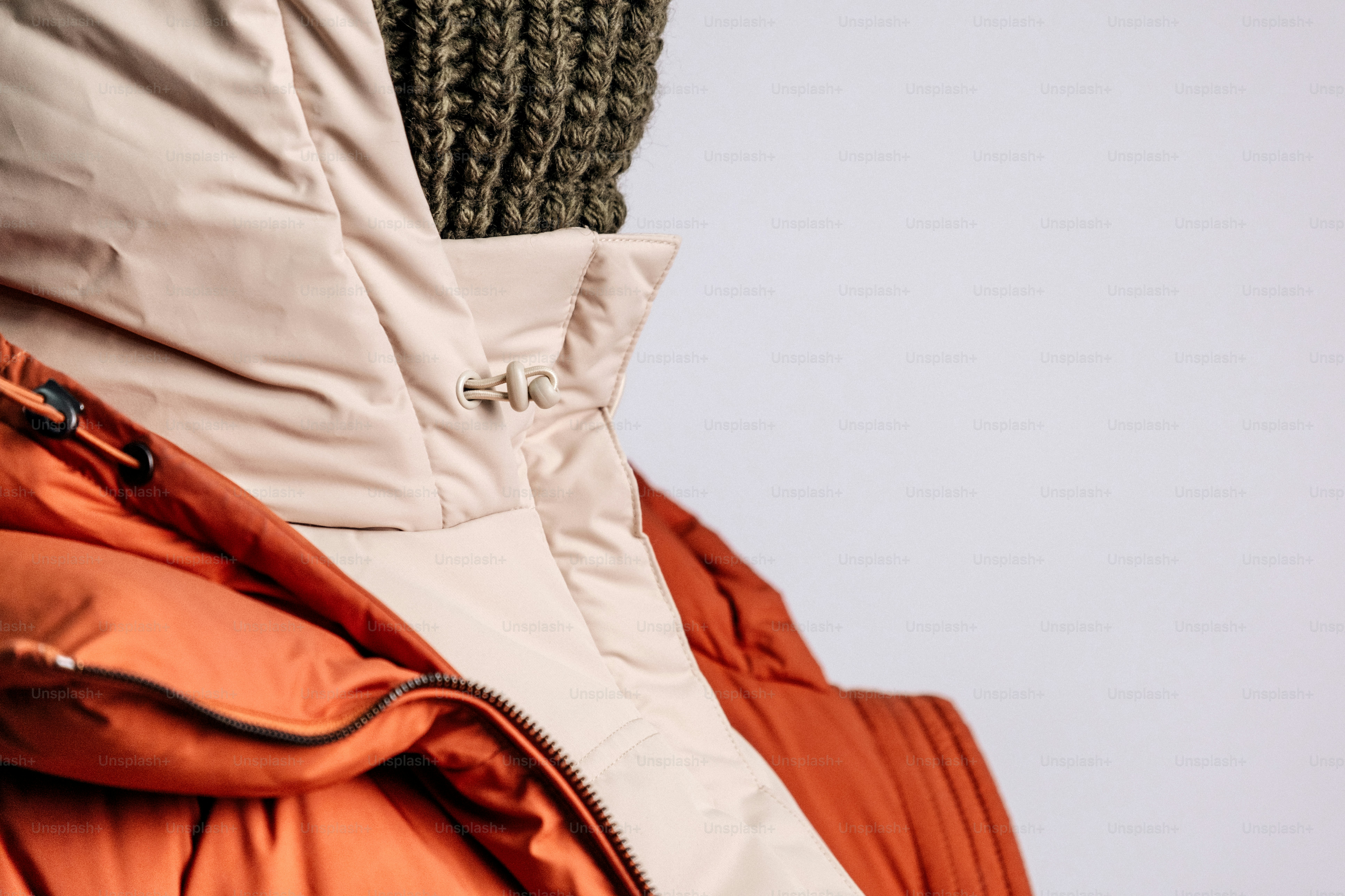 Close-up seseorang yang mengenakan jaket puffer dan beanie.