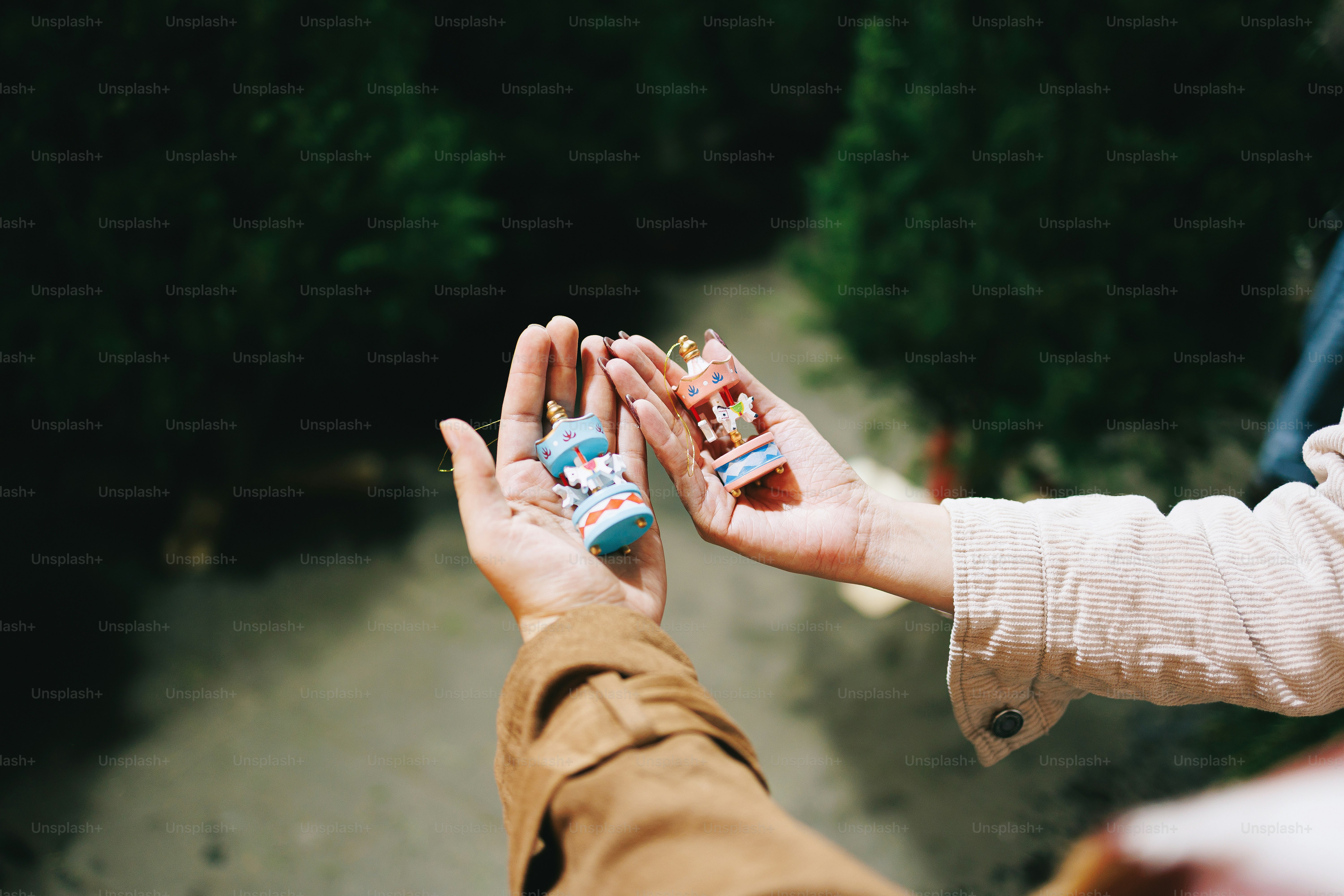 Hands holding small objects against dark background