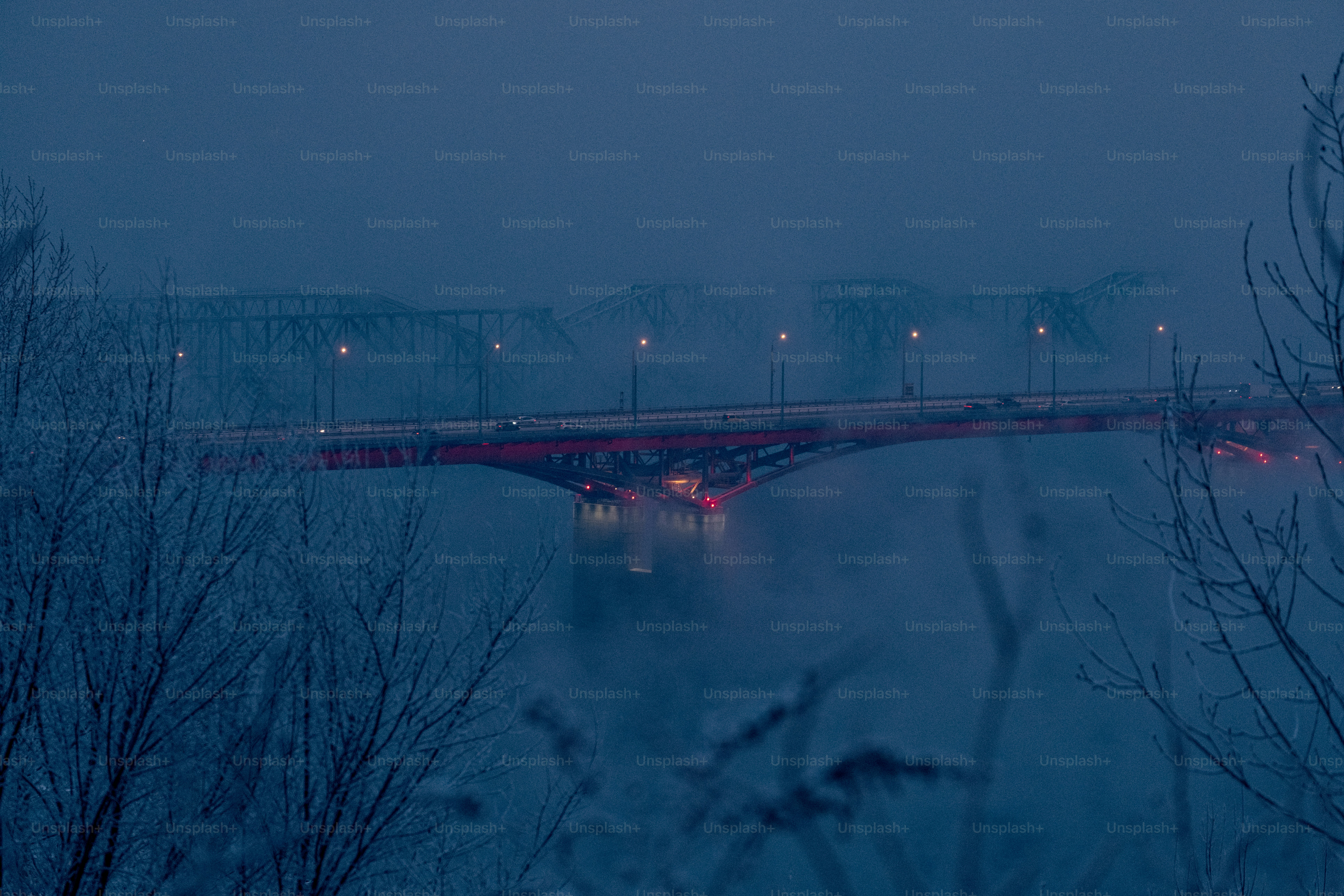Bridge illuminated at dusk over a misty river