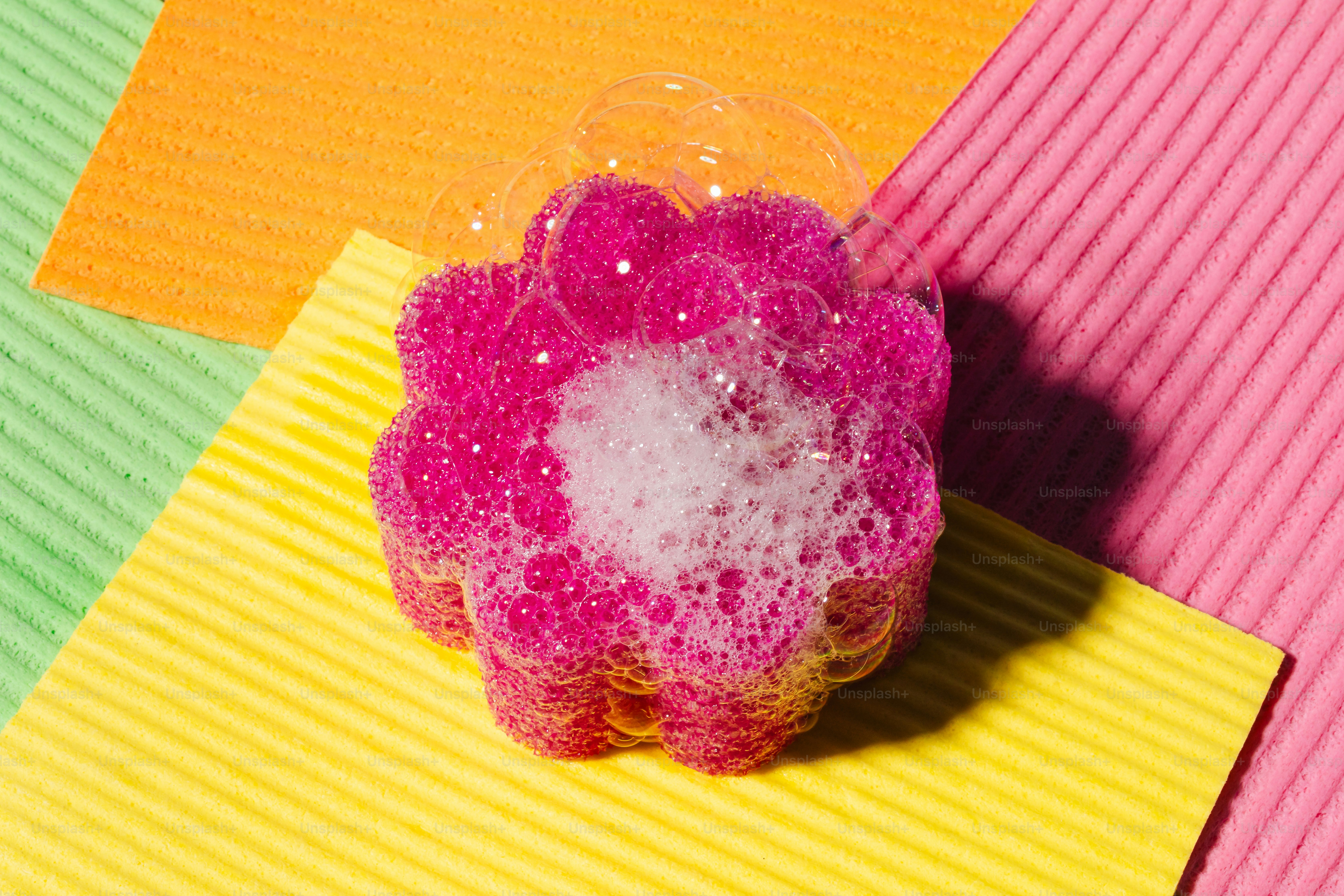 Pink flower-shaped sponge with soap bubbles.