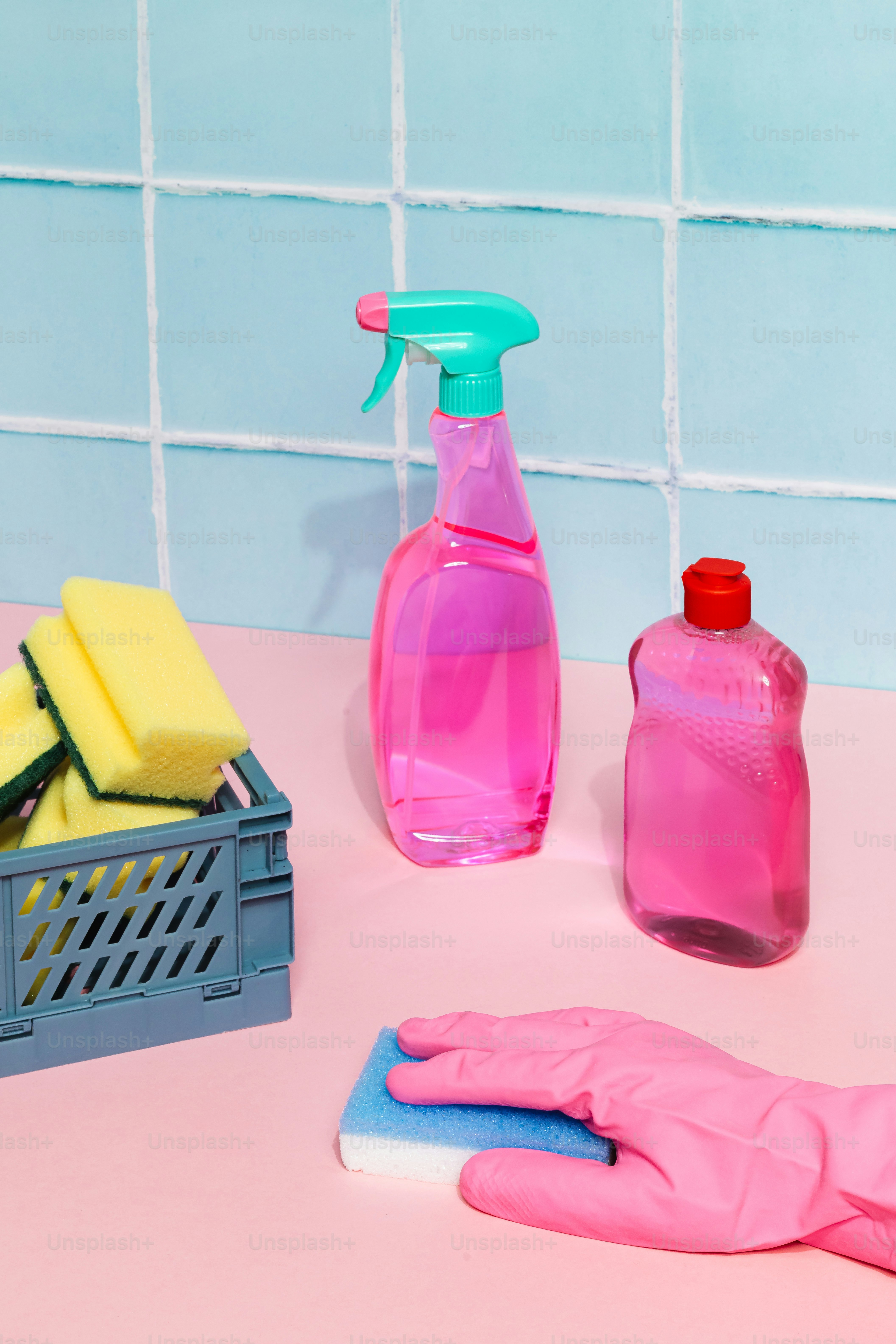 Pink cleaning spray bottle with sponges and pink glove.