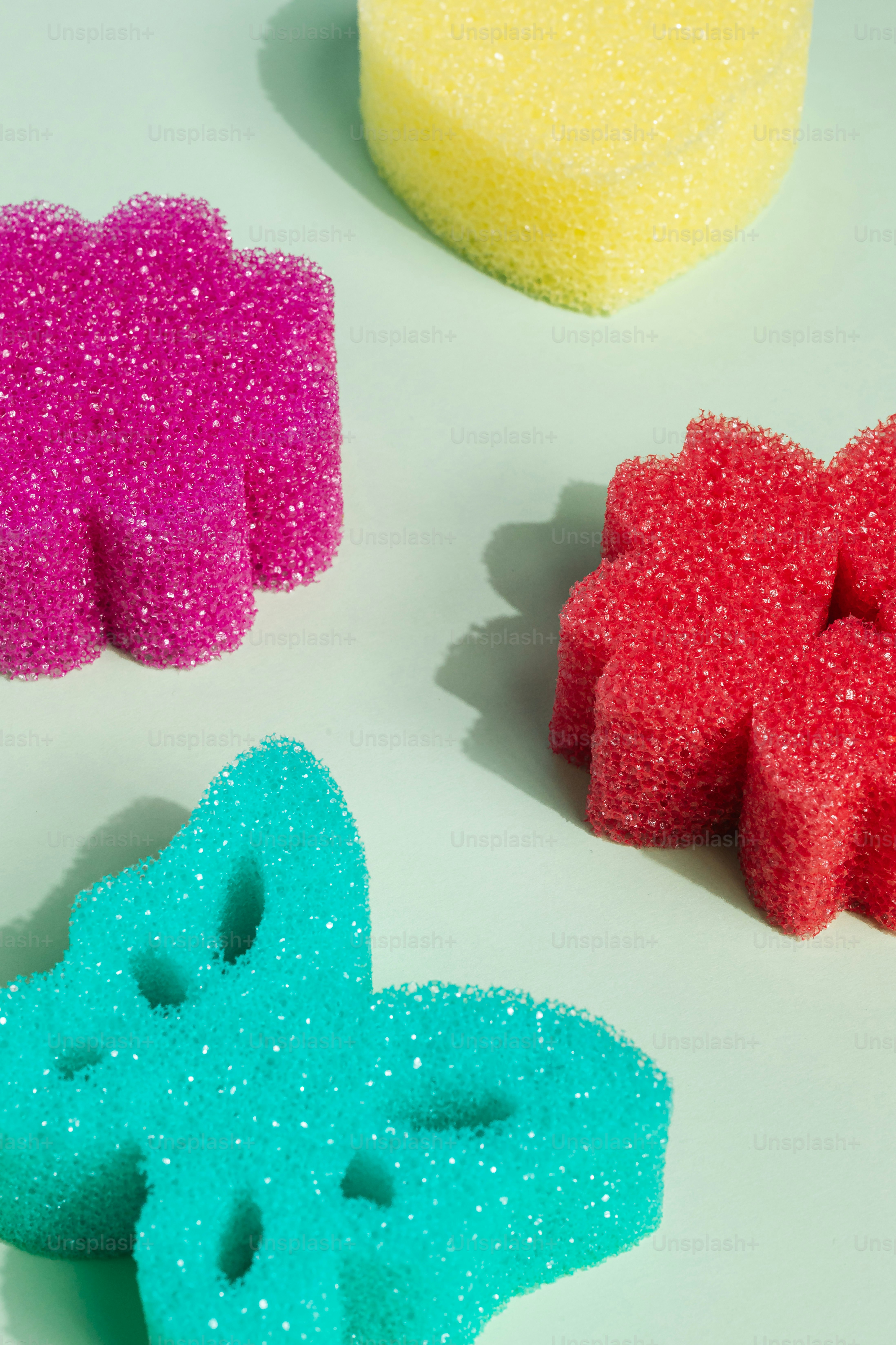 Four colorful sponges on a light green surface.