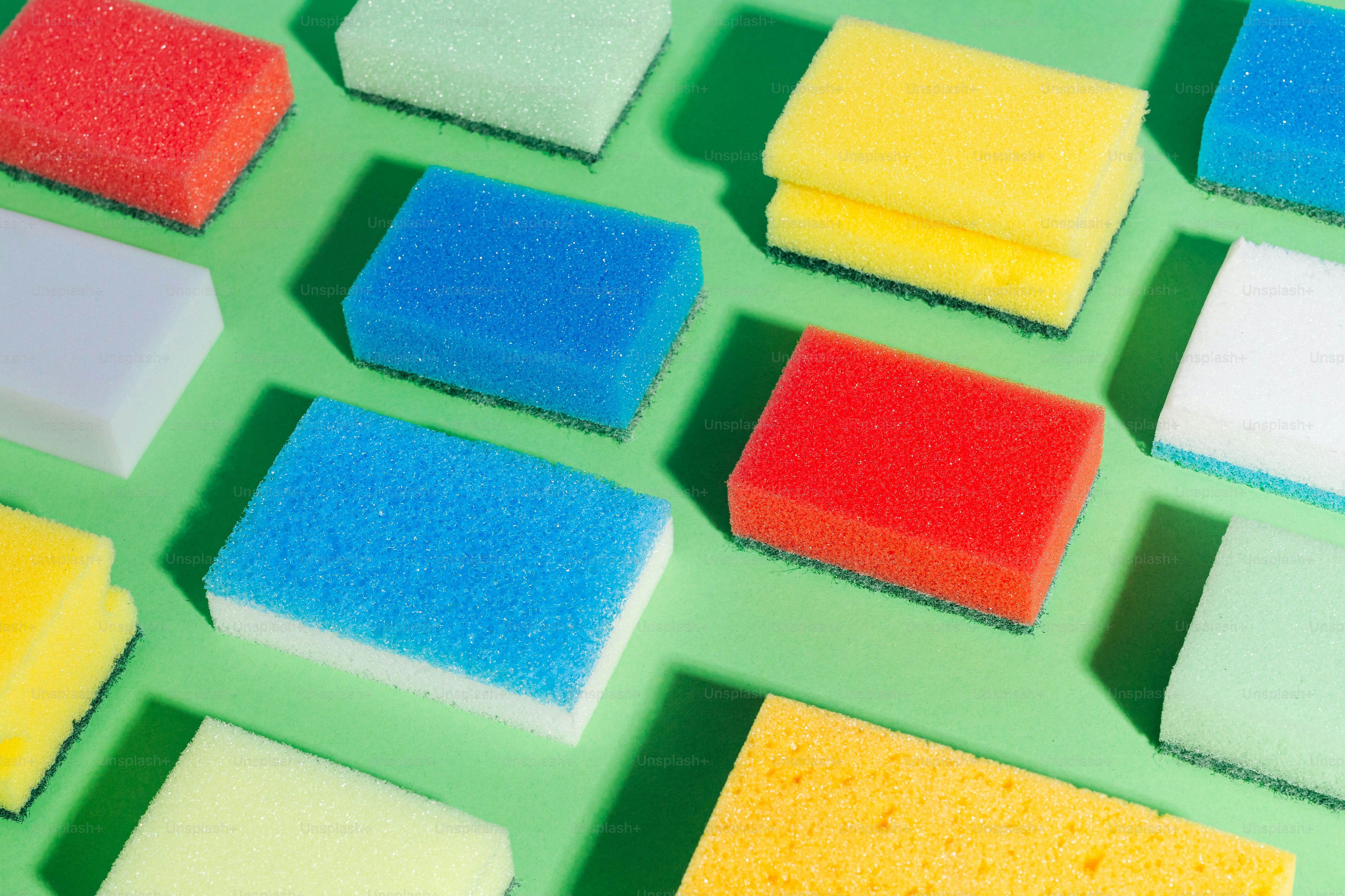 Colorful cleaning sponges arranged on a green background