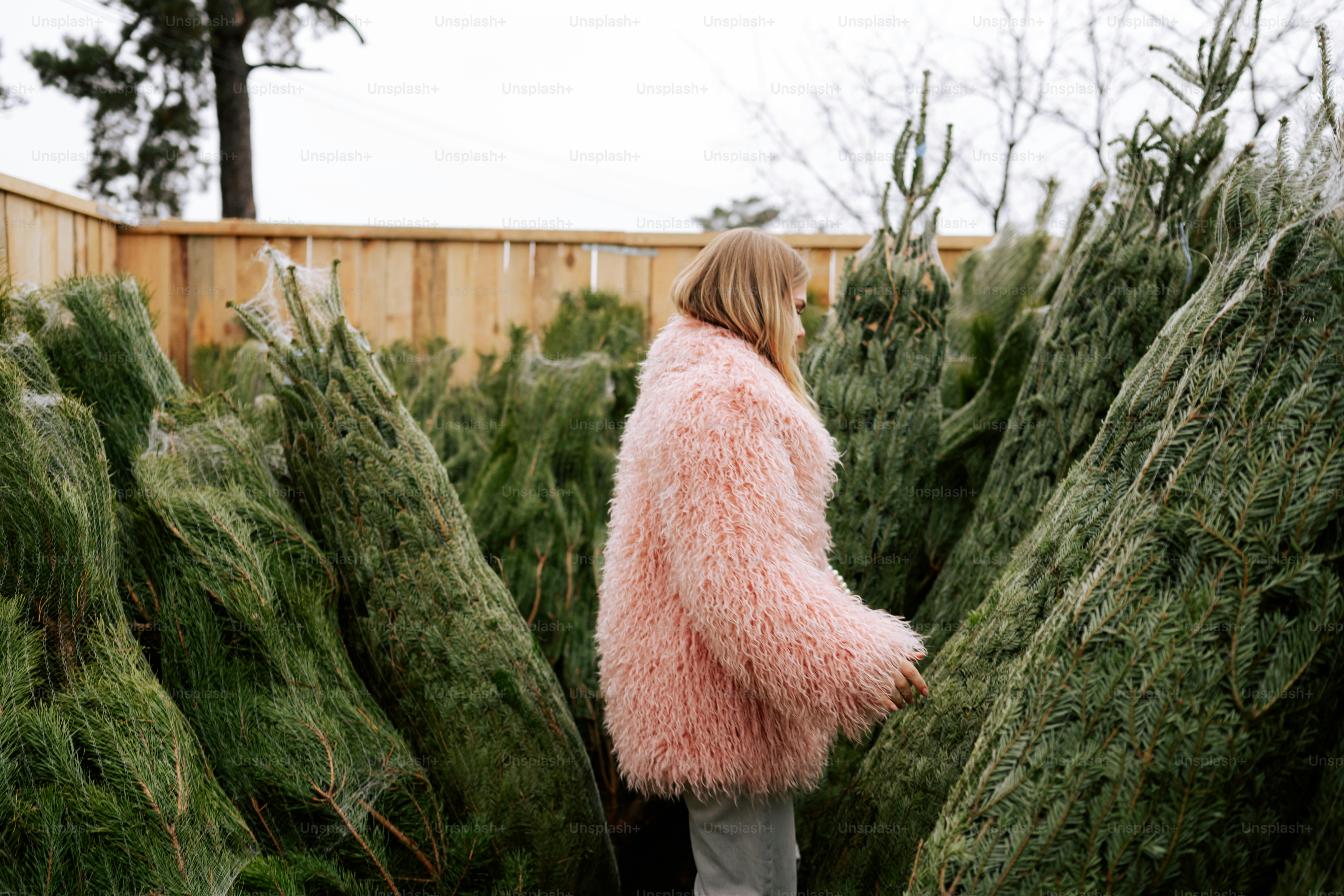 Woman in pink coat among christmas trees