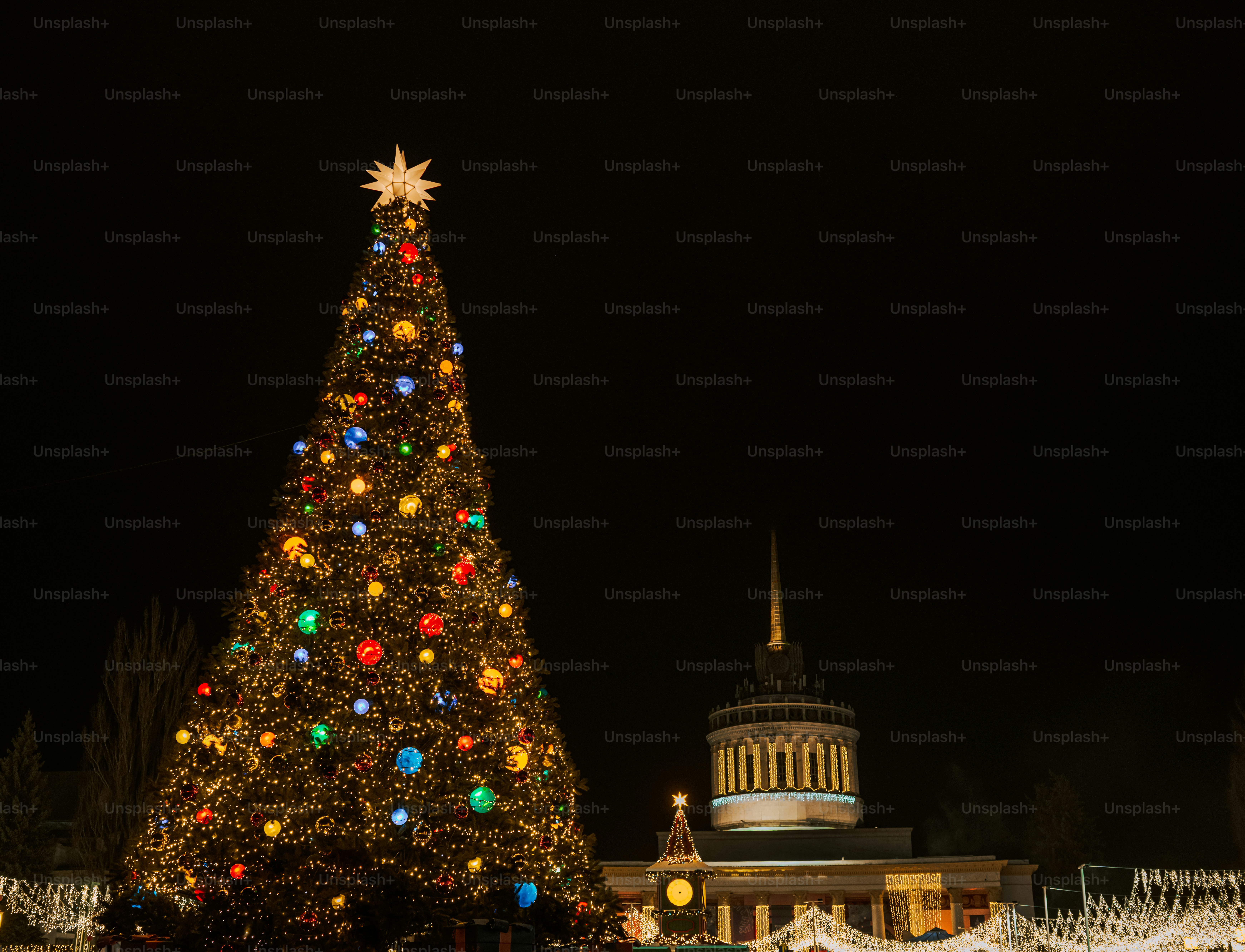 Decorated christmas tree at night with building.