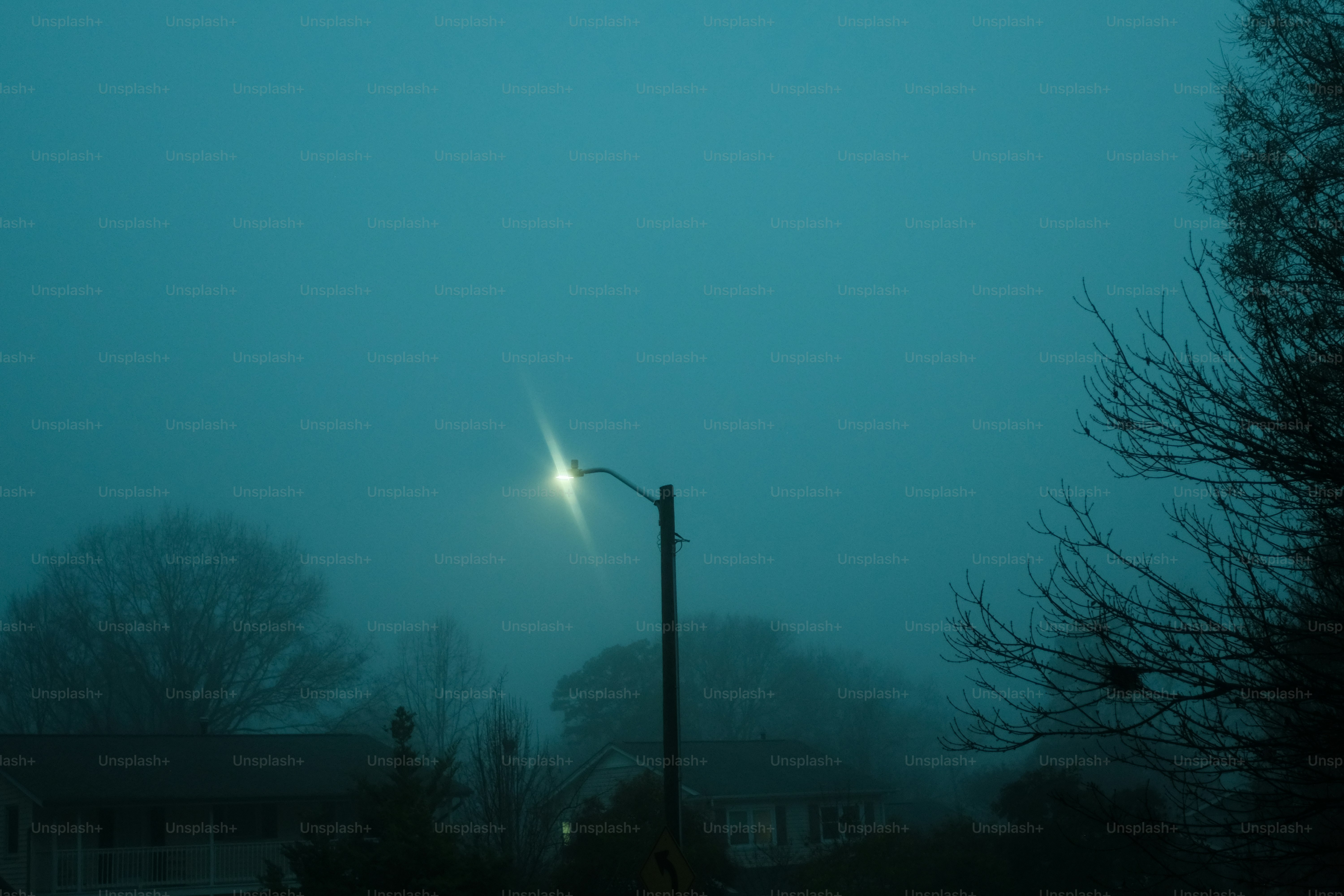 Streetlight glowing through dense fog at night.