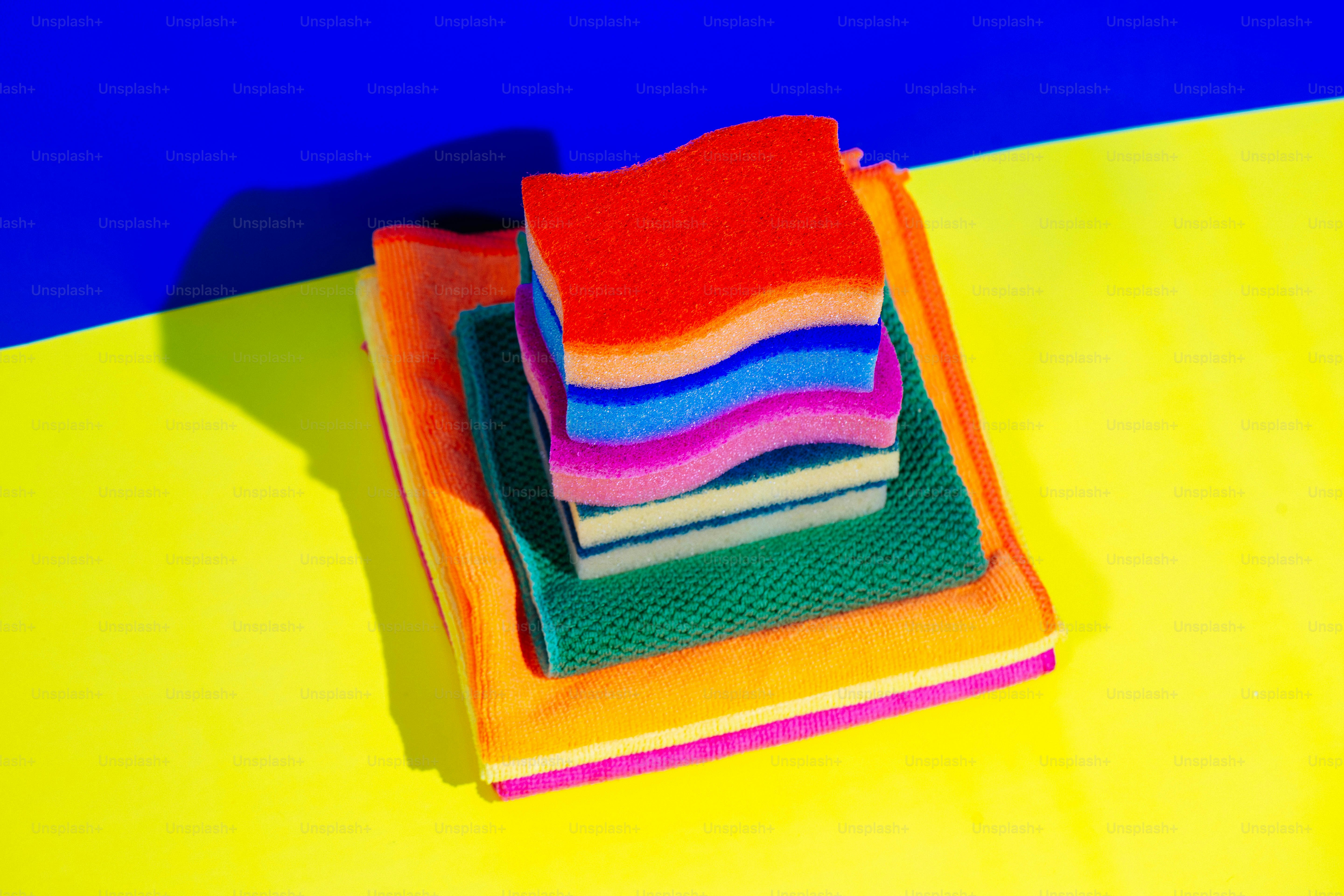 Esponjas e panos de limpeza coloridos empilhados sobre uma superfície.