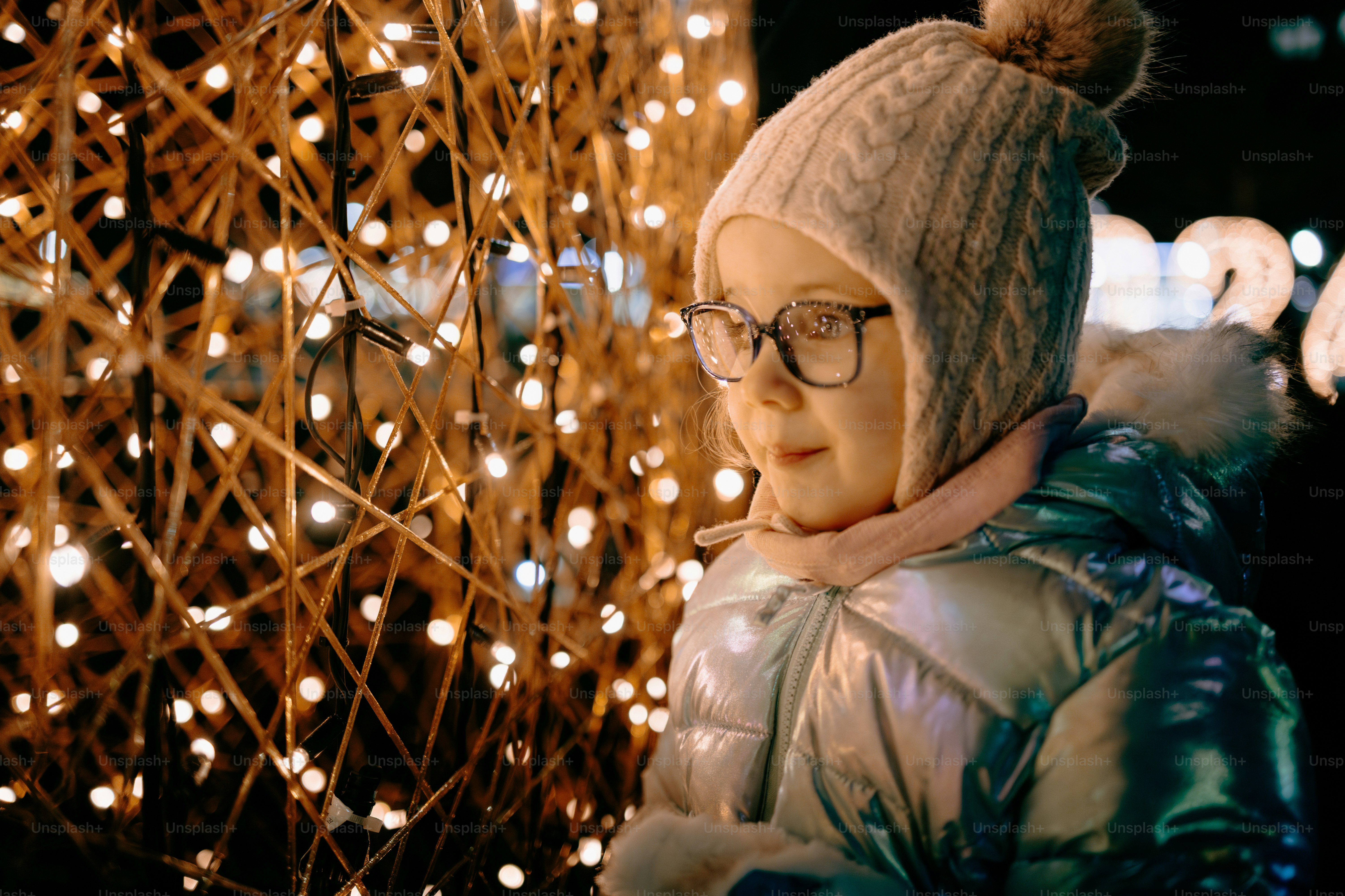 Joven con sombrero y abrigo de invierno cerca de las luces