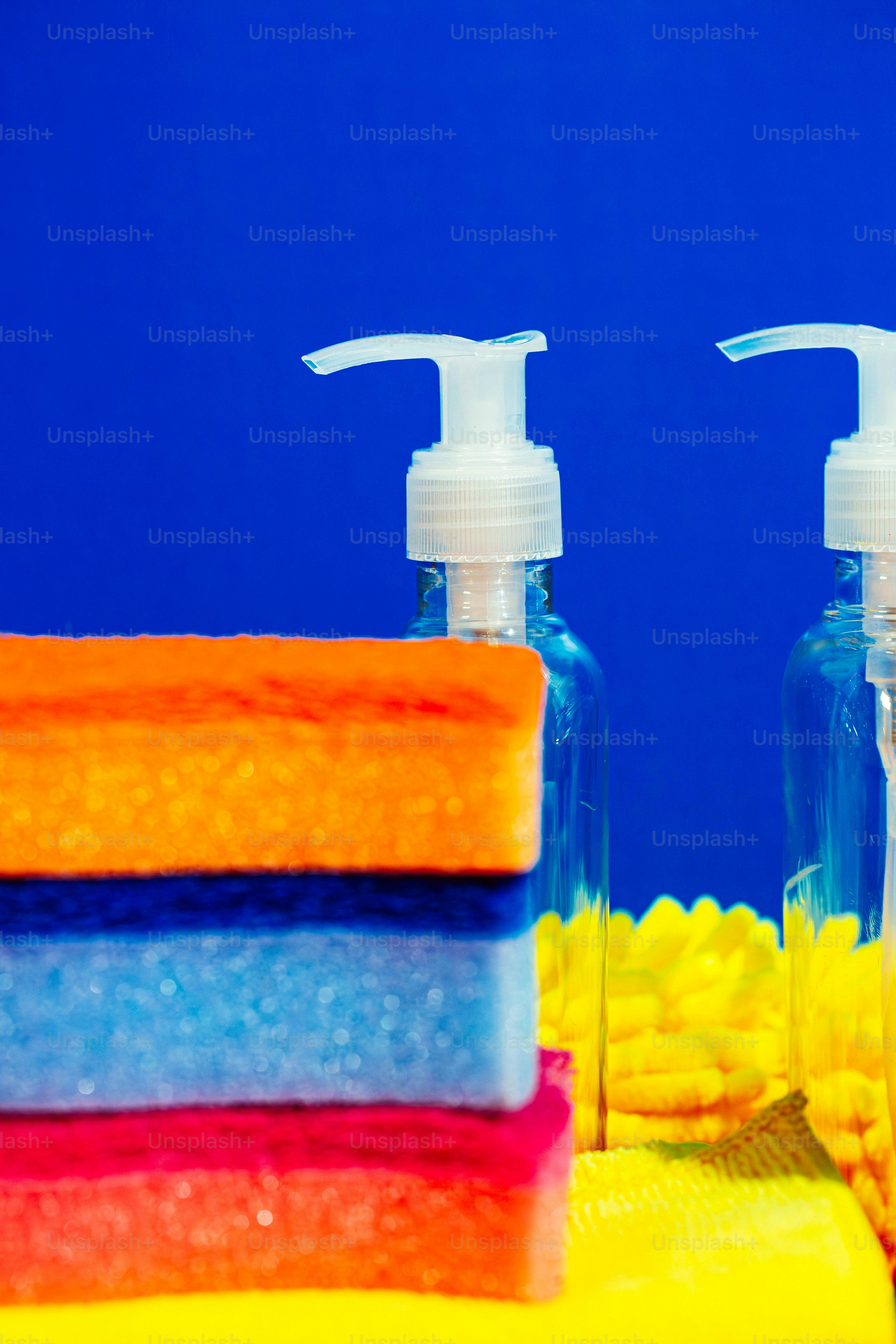 Esponjas coloridas e dispensadores de sabonete sobre fundo azul