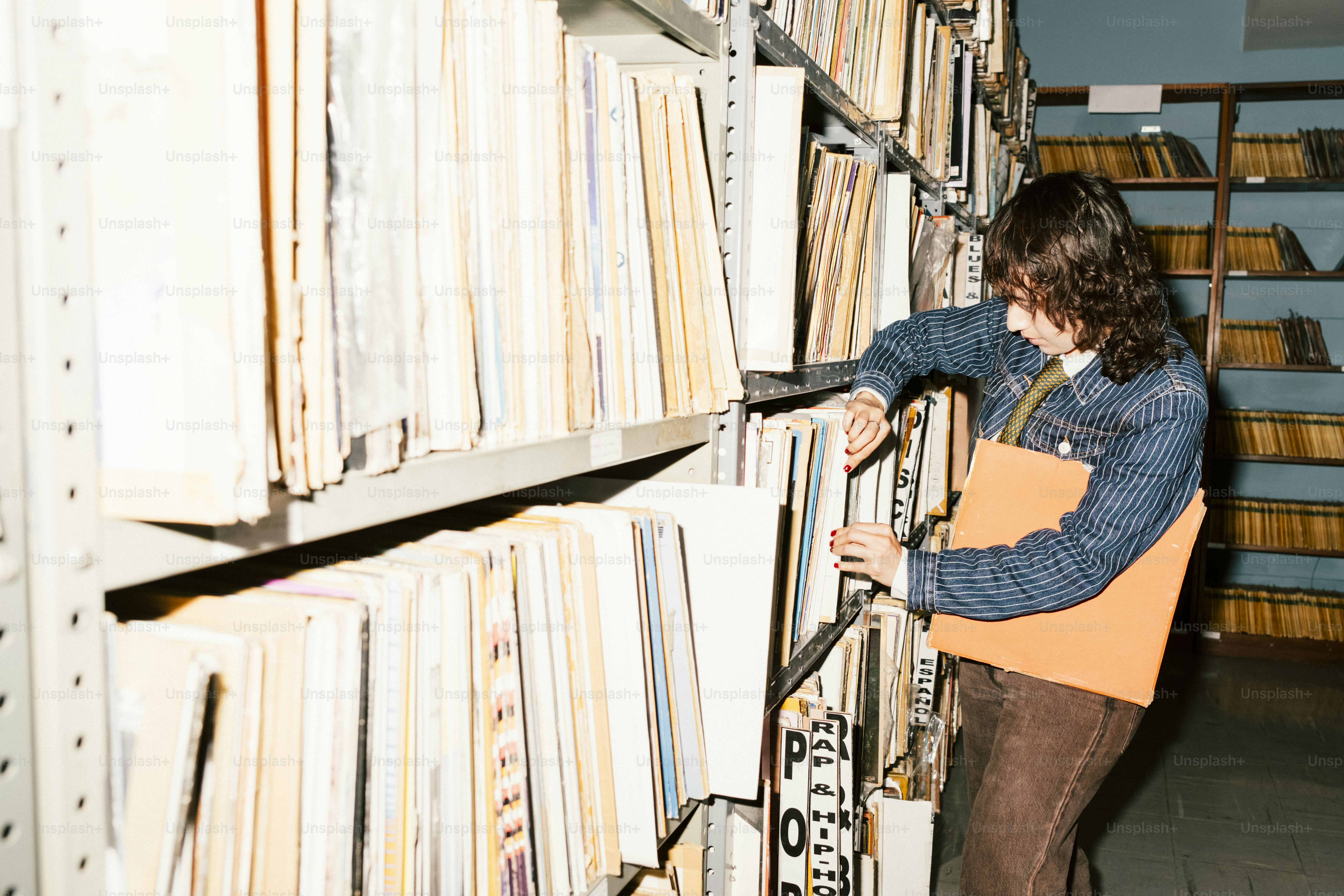 Person searching through files on a shelf.
