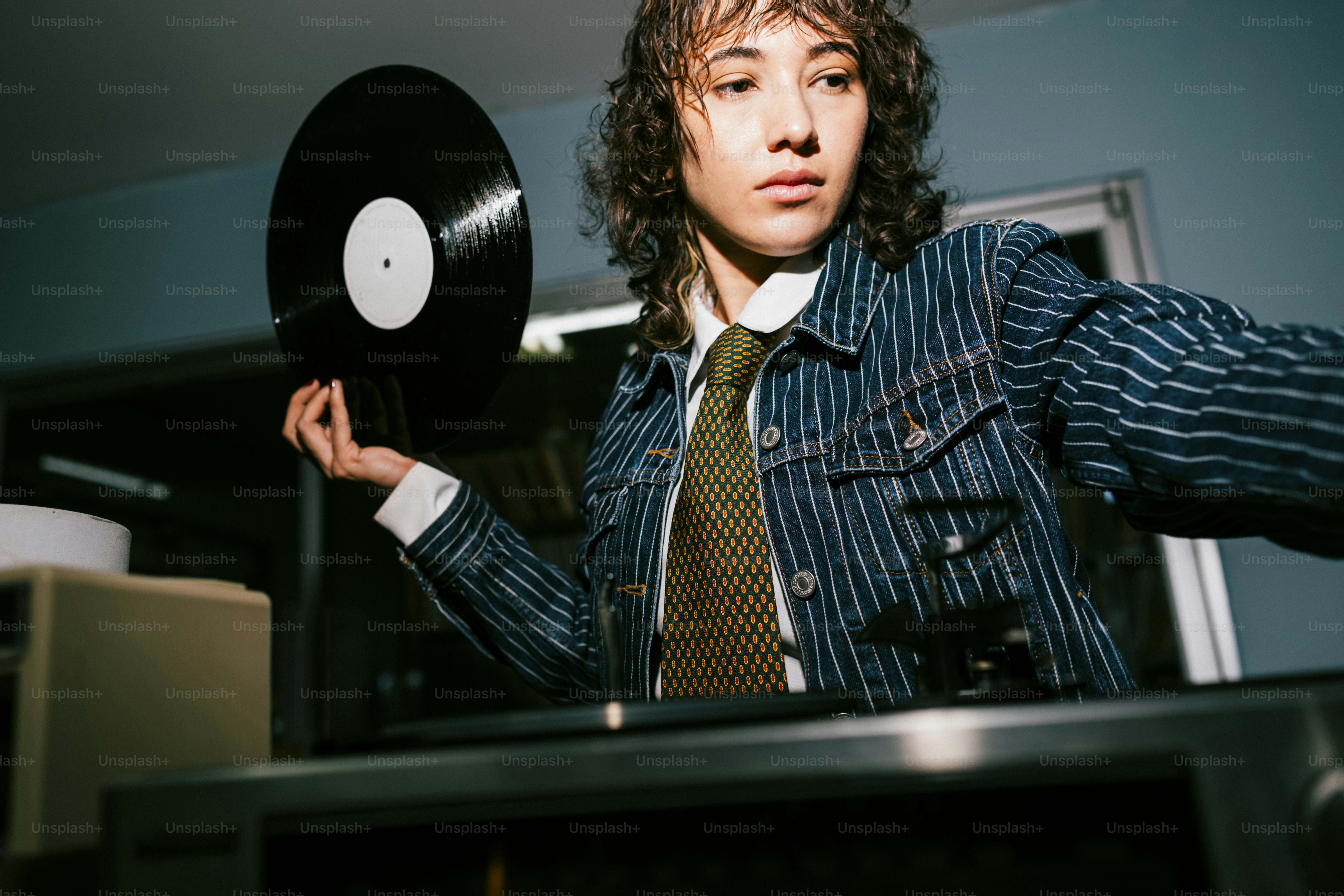A person holding a vinyl record near a turntable.