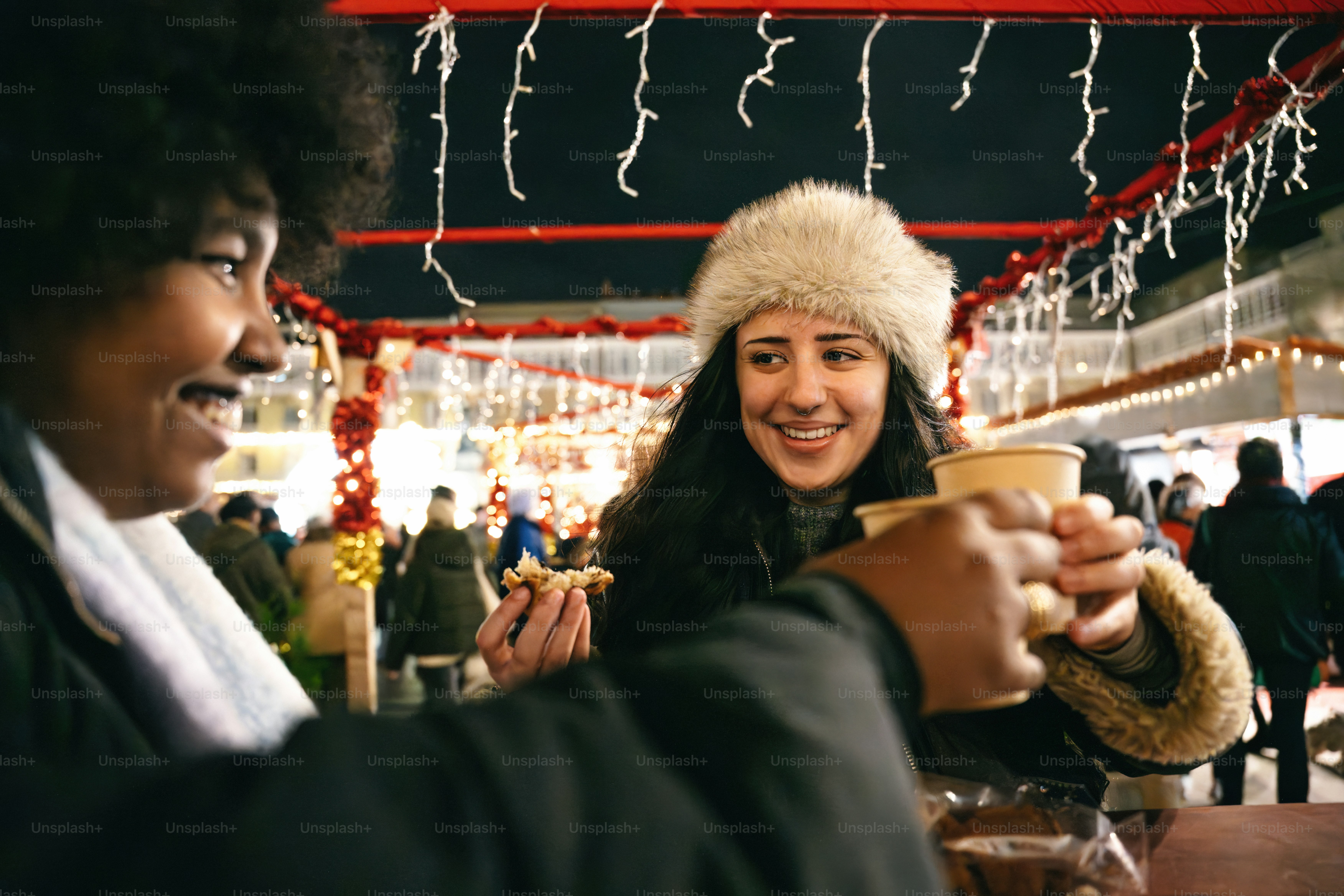 Due donne brindano a bere in un mercato all'aperto festoso.
