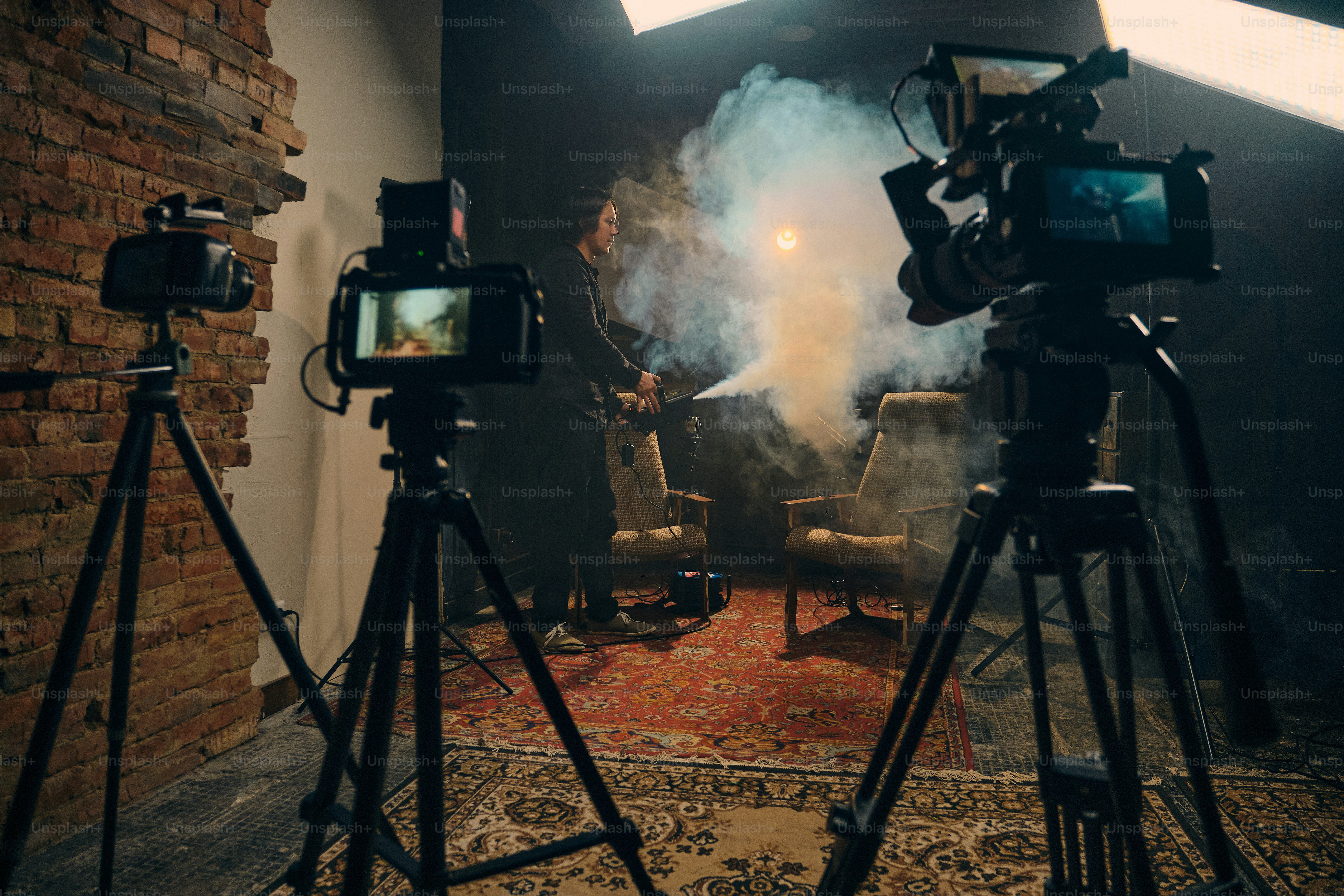 Two cameras filming a person in a dimly lit studio. photo – Camera ...
