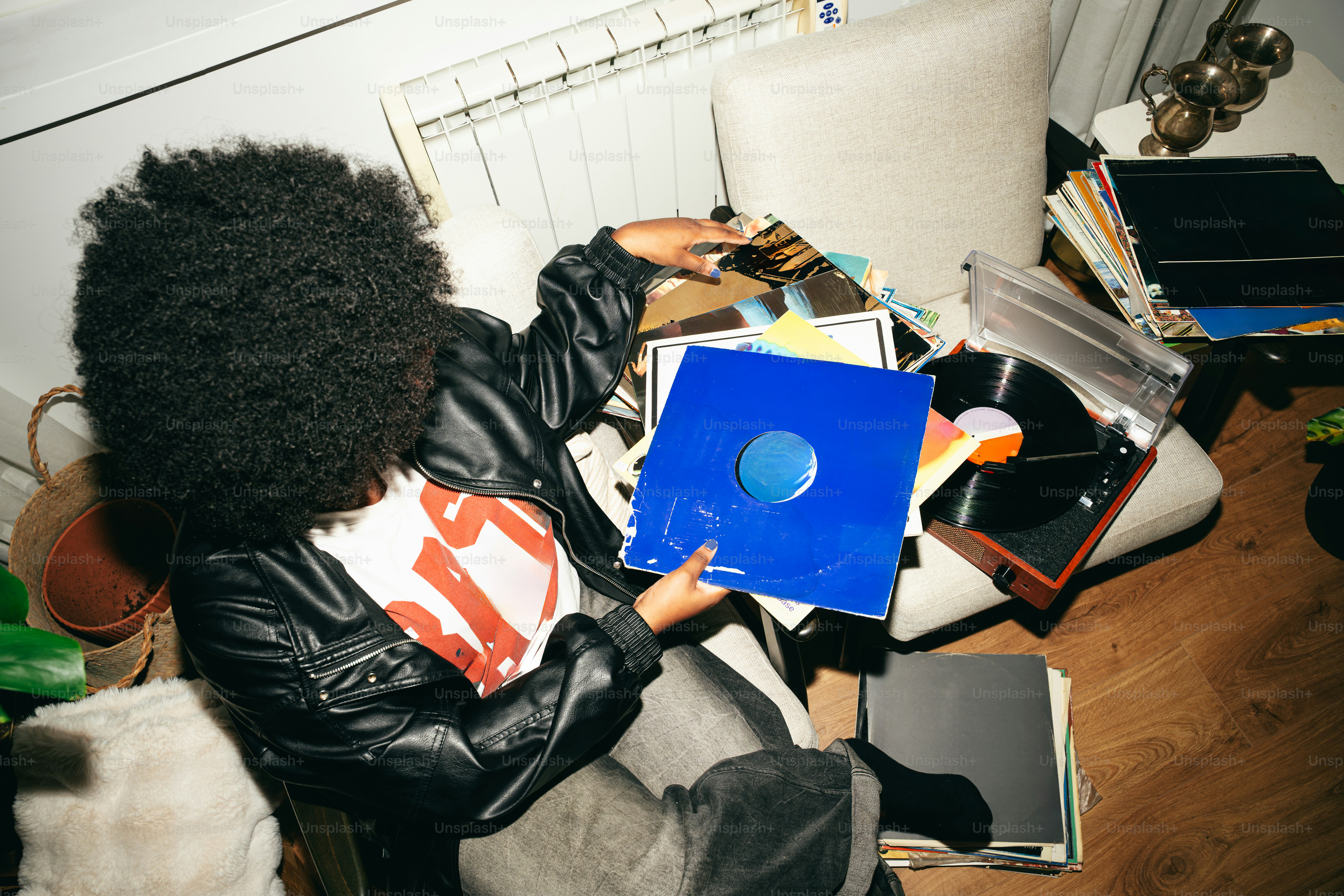 Person holding a blue record sleeve in cluttered room