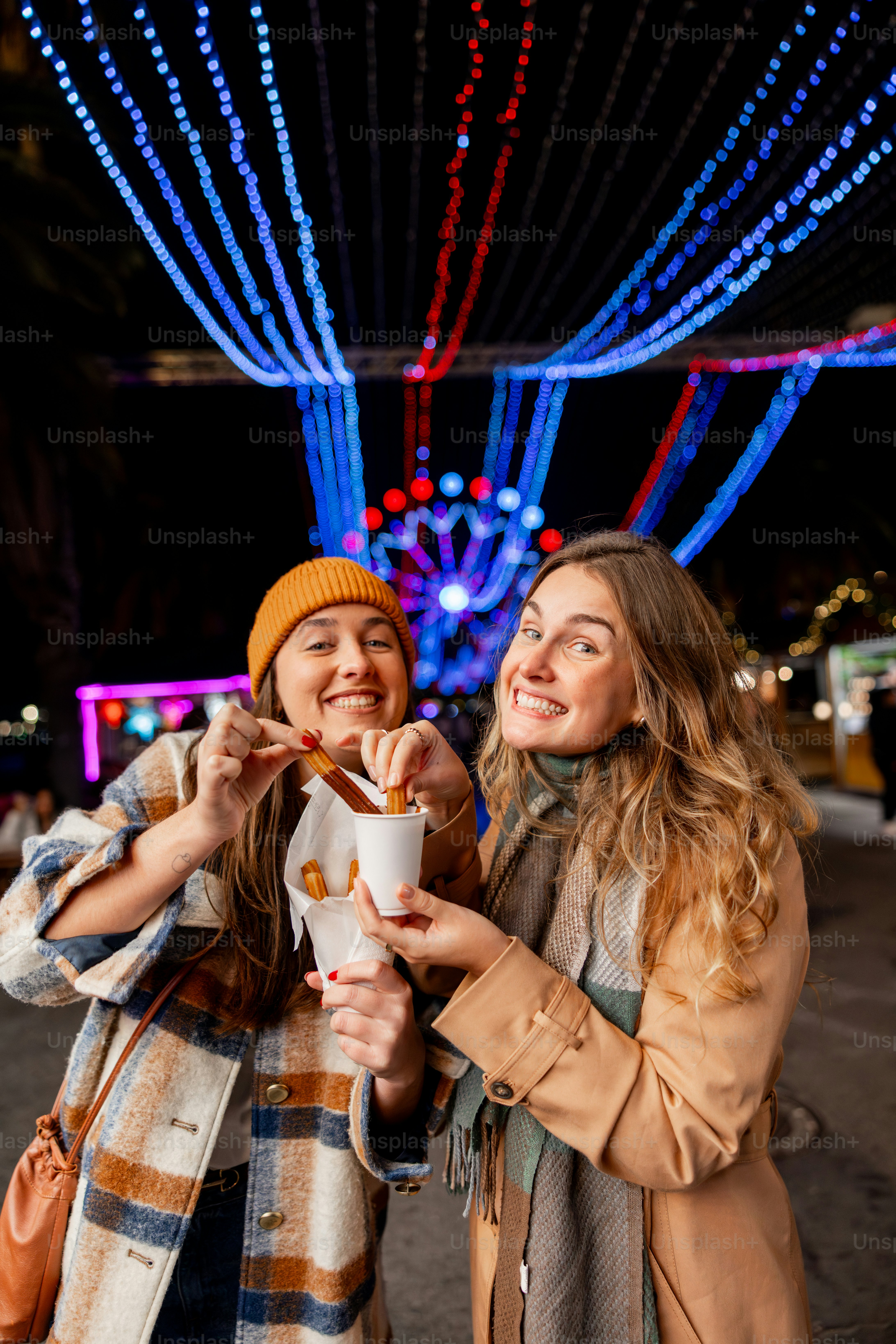 夜にチュロスを食べる二人の笑顔の女性