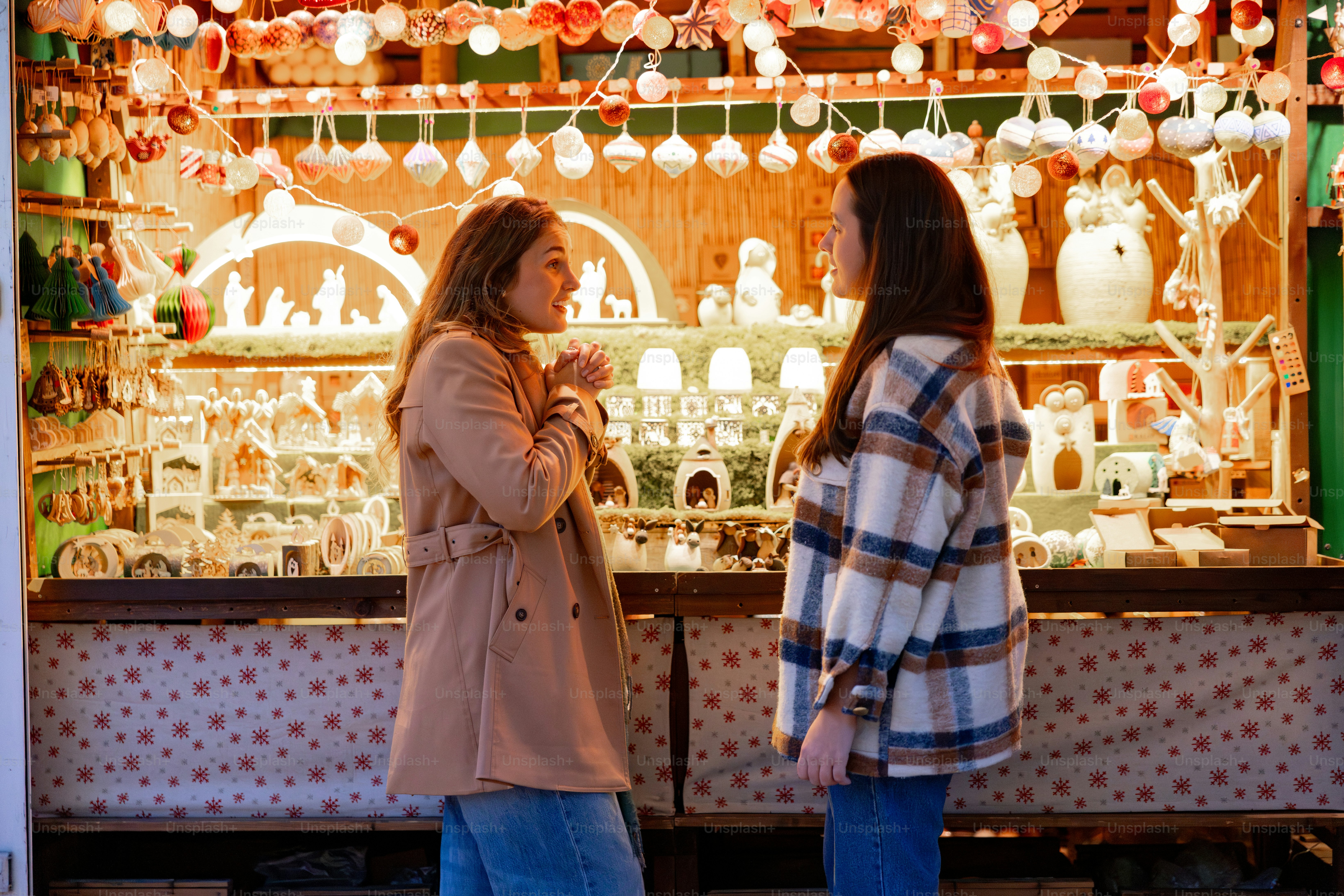 Two women talking at a christmas market stall.