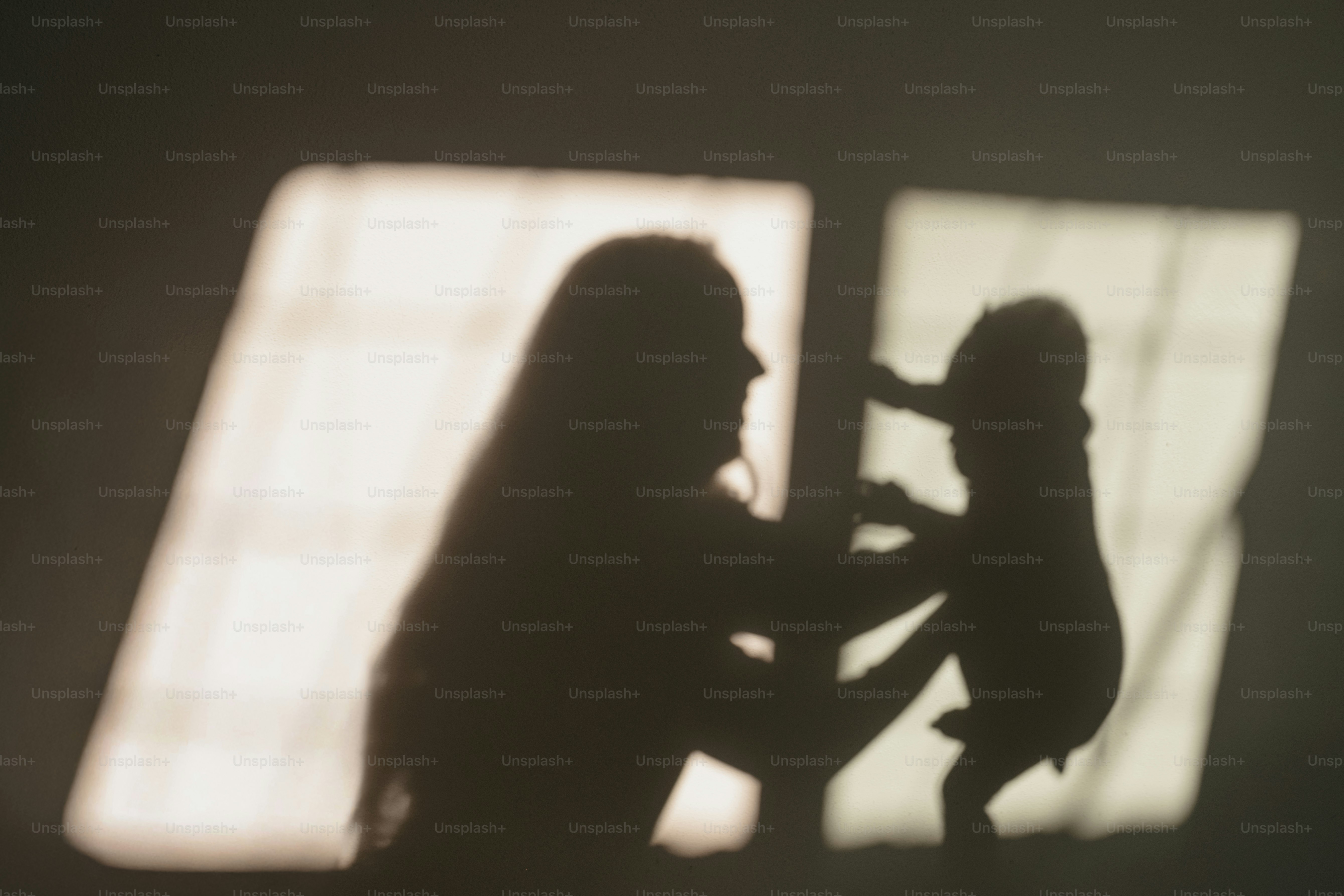 Silhouette der Mutter, die das Baby am Fenster hält