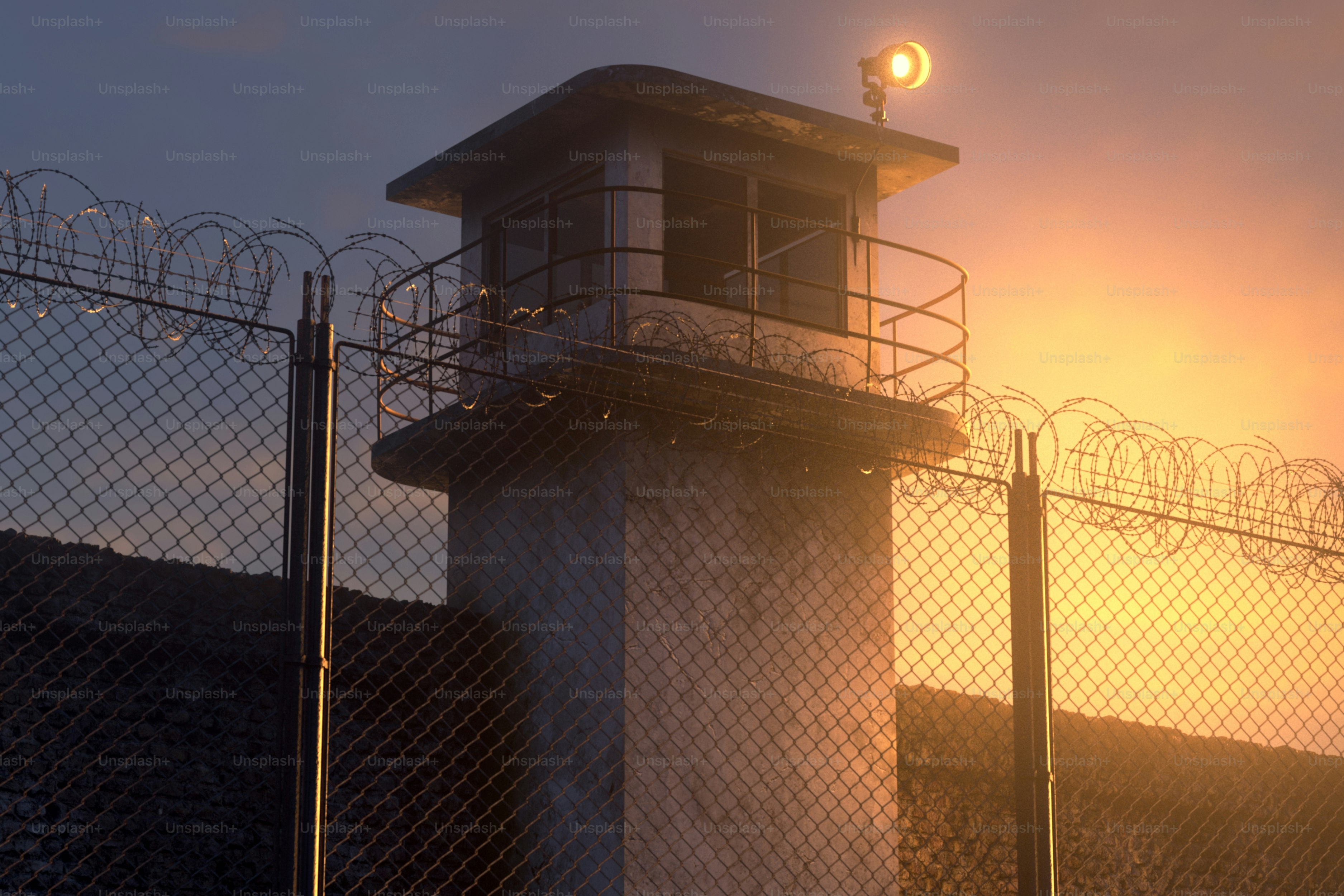 Torre de vigilancia con valla de alambre de espino al atardecer
