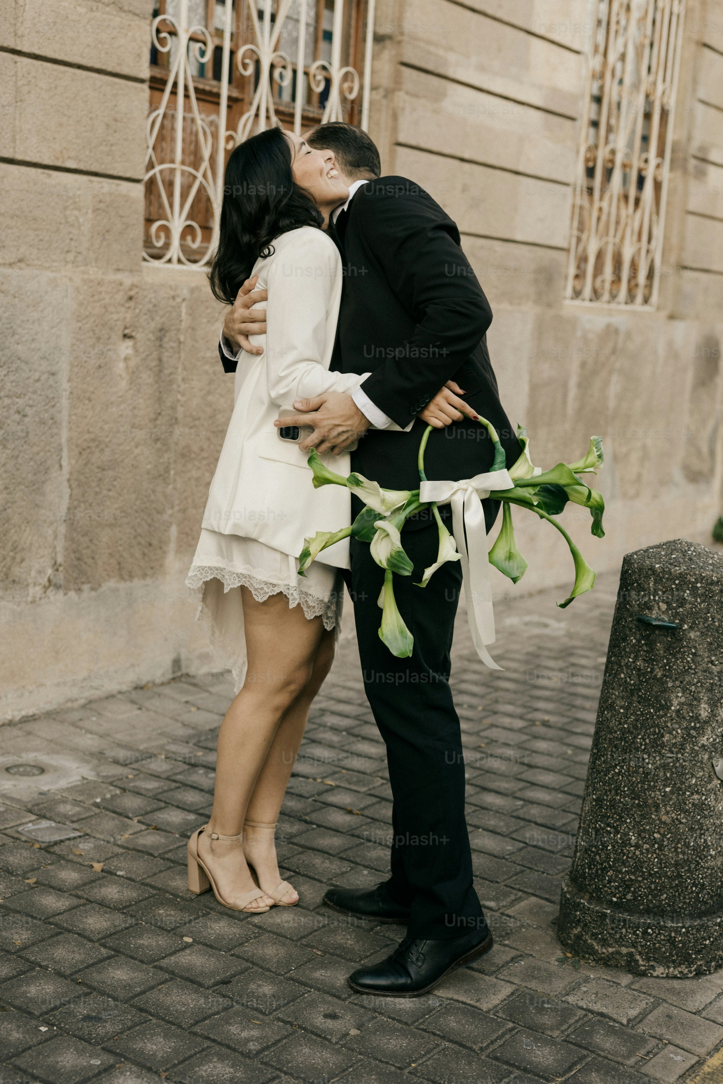 Ein Paar, das sich mit einem Strauß Lilien küsst.