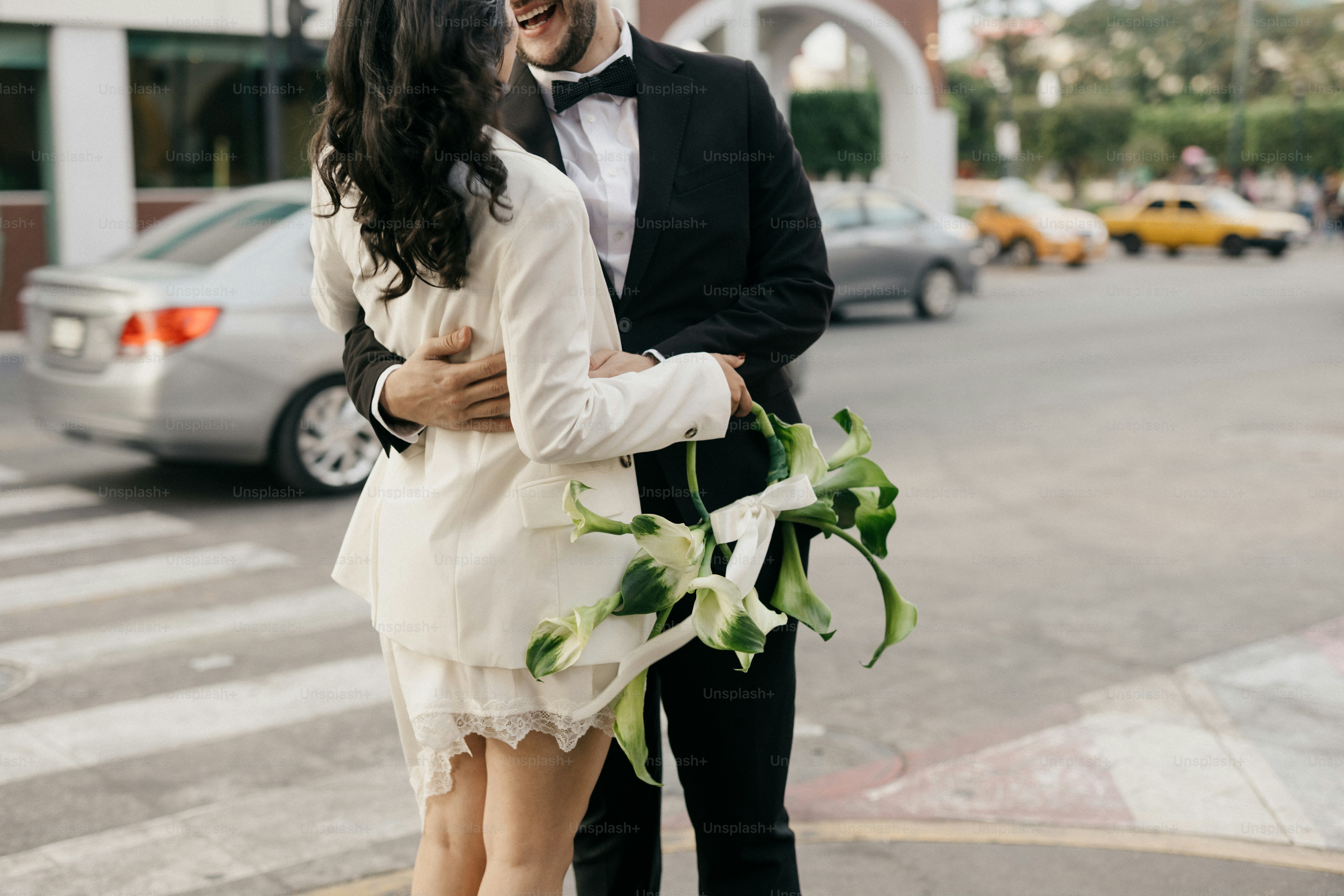 Paar in Hochzeitskleidung umarmt sich mit Blumen