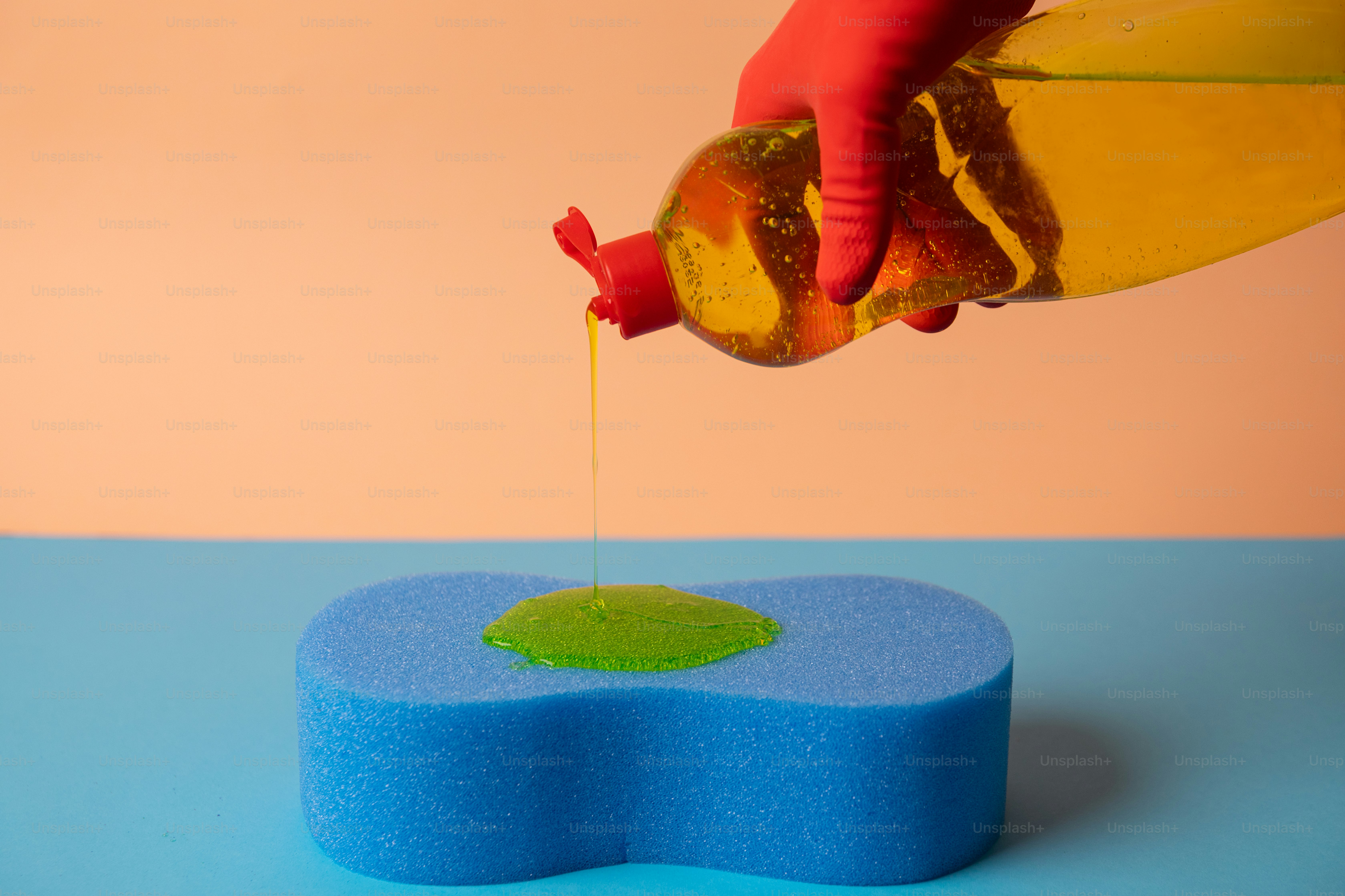Du liquide vaisselle versé sur une éponge bleue.