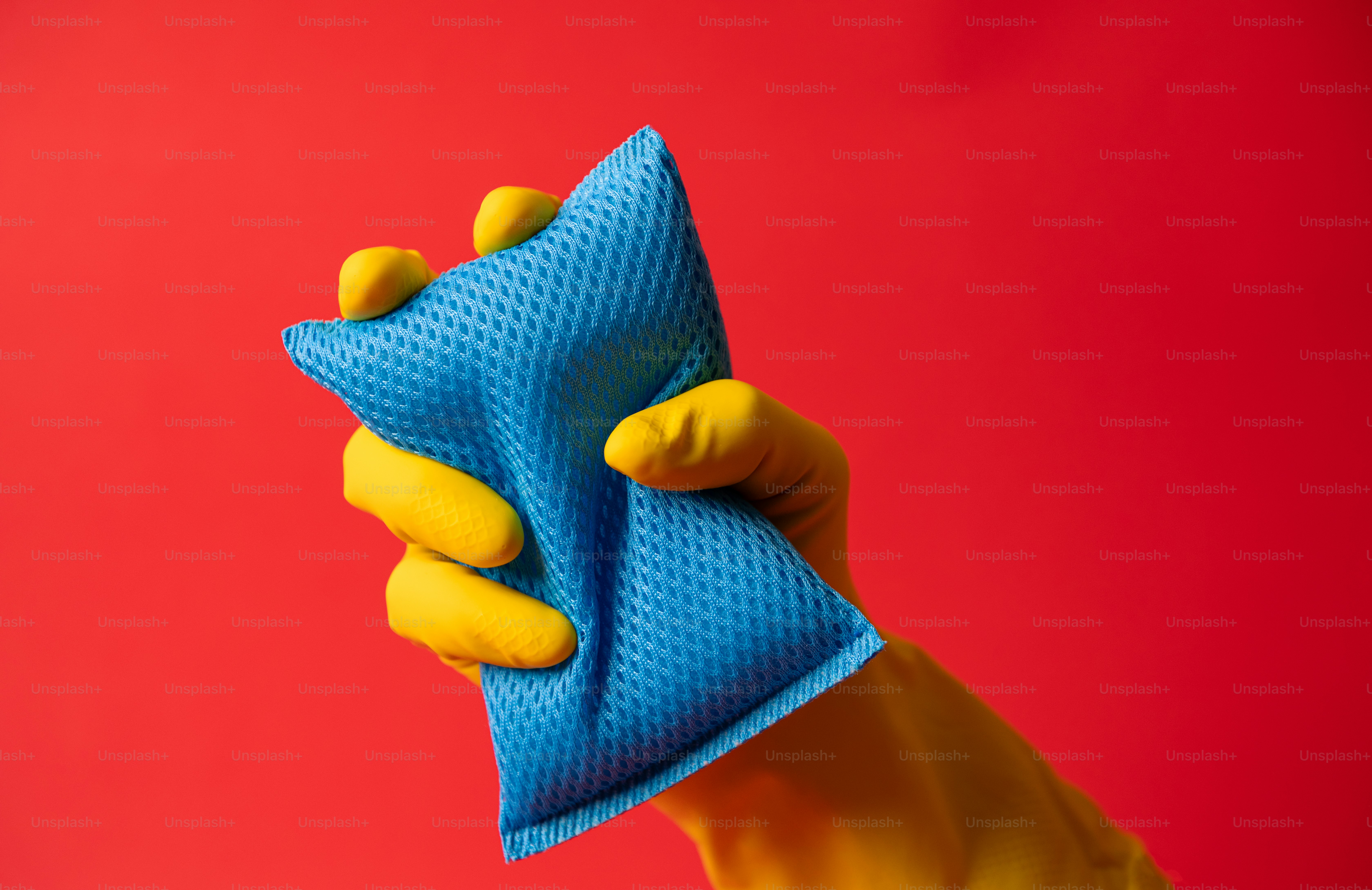 La main dans le gant jaune tient une éponge nettoyante bleue