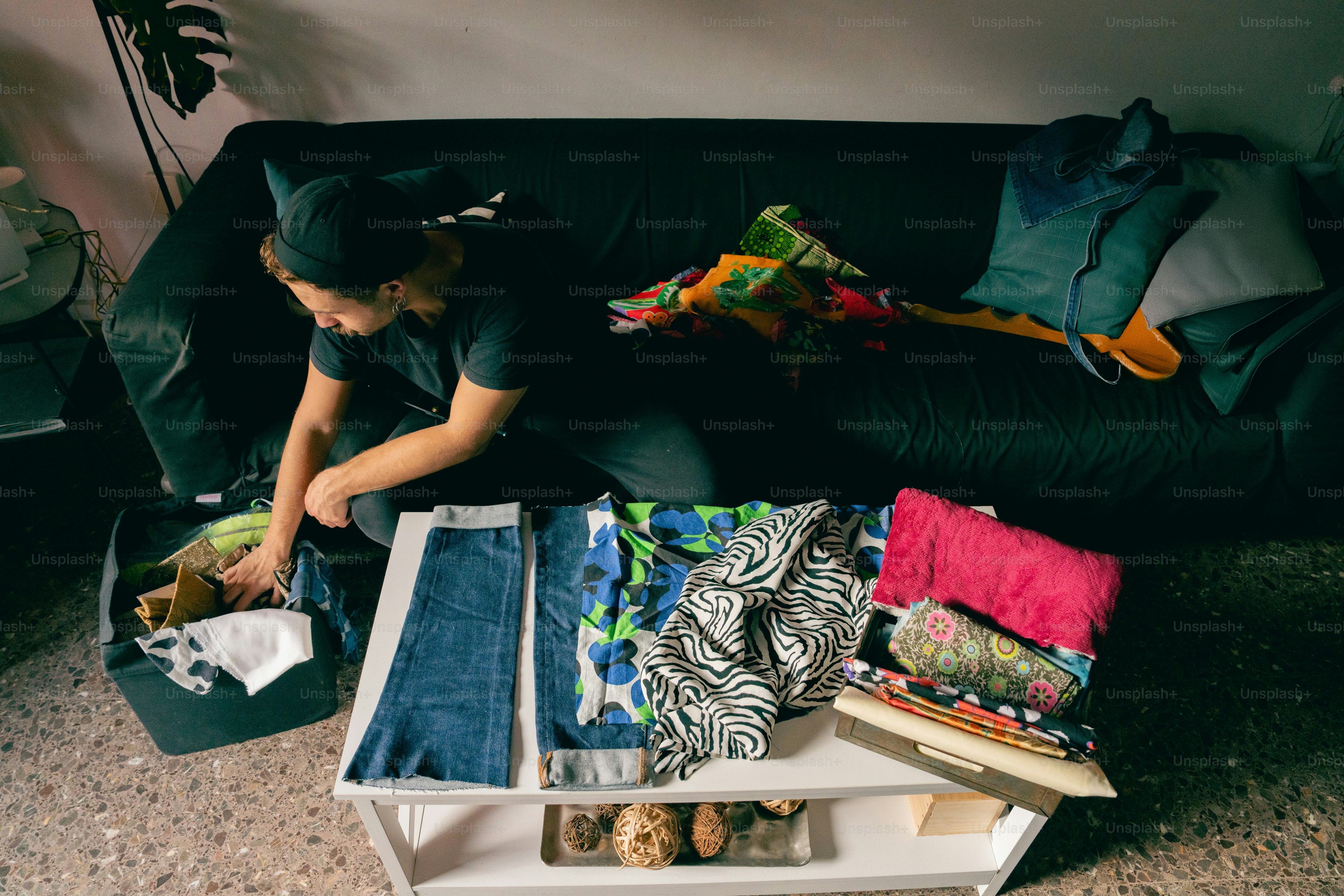 Person sorting clothes on a table and couch. photo – Sustainability ...