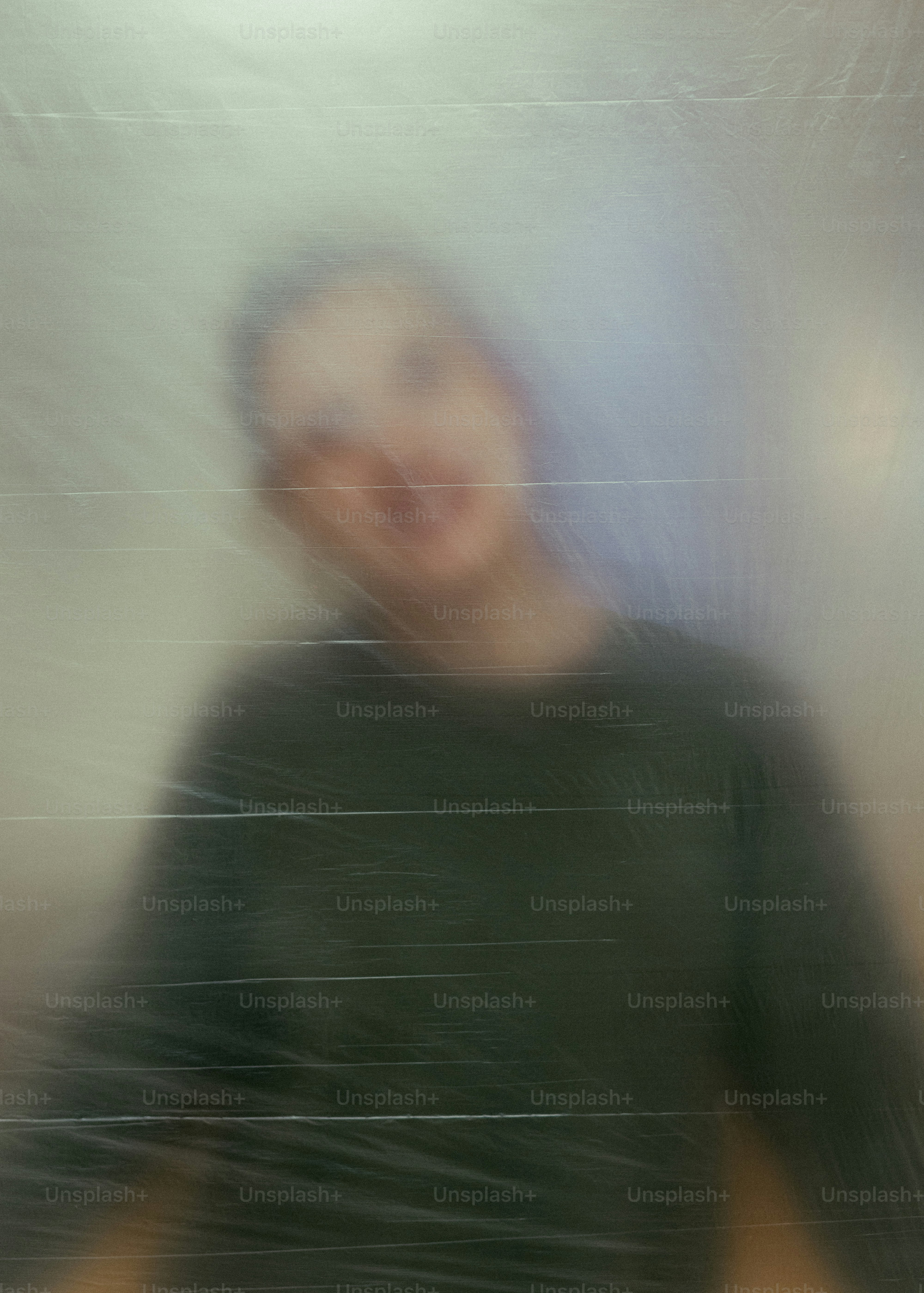 Persona borrosa detrás de una superficie translúcida texturizada