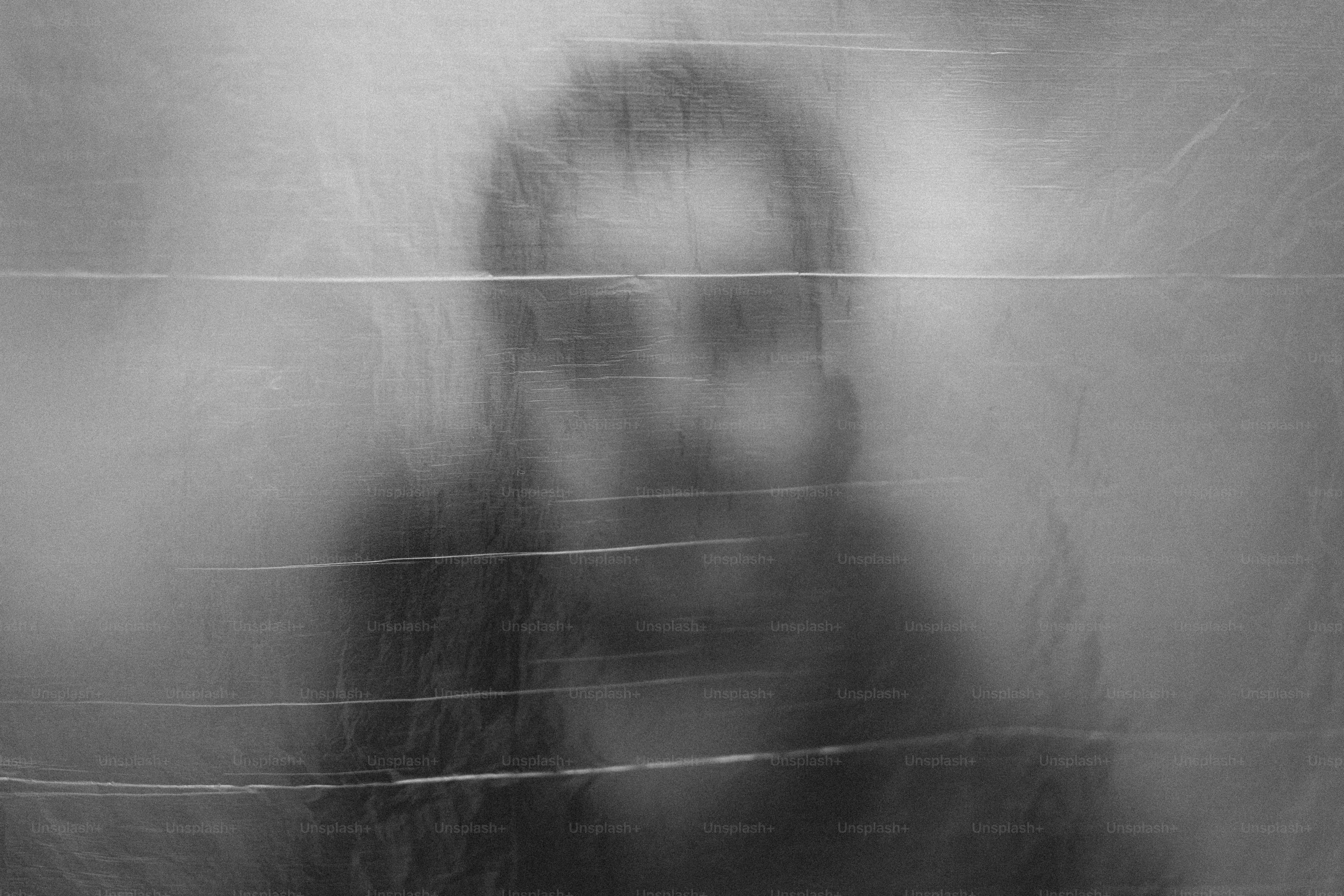 Blurred man behind a textured, translucent surface.
