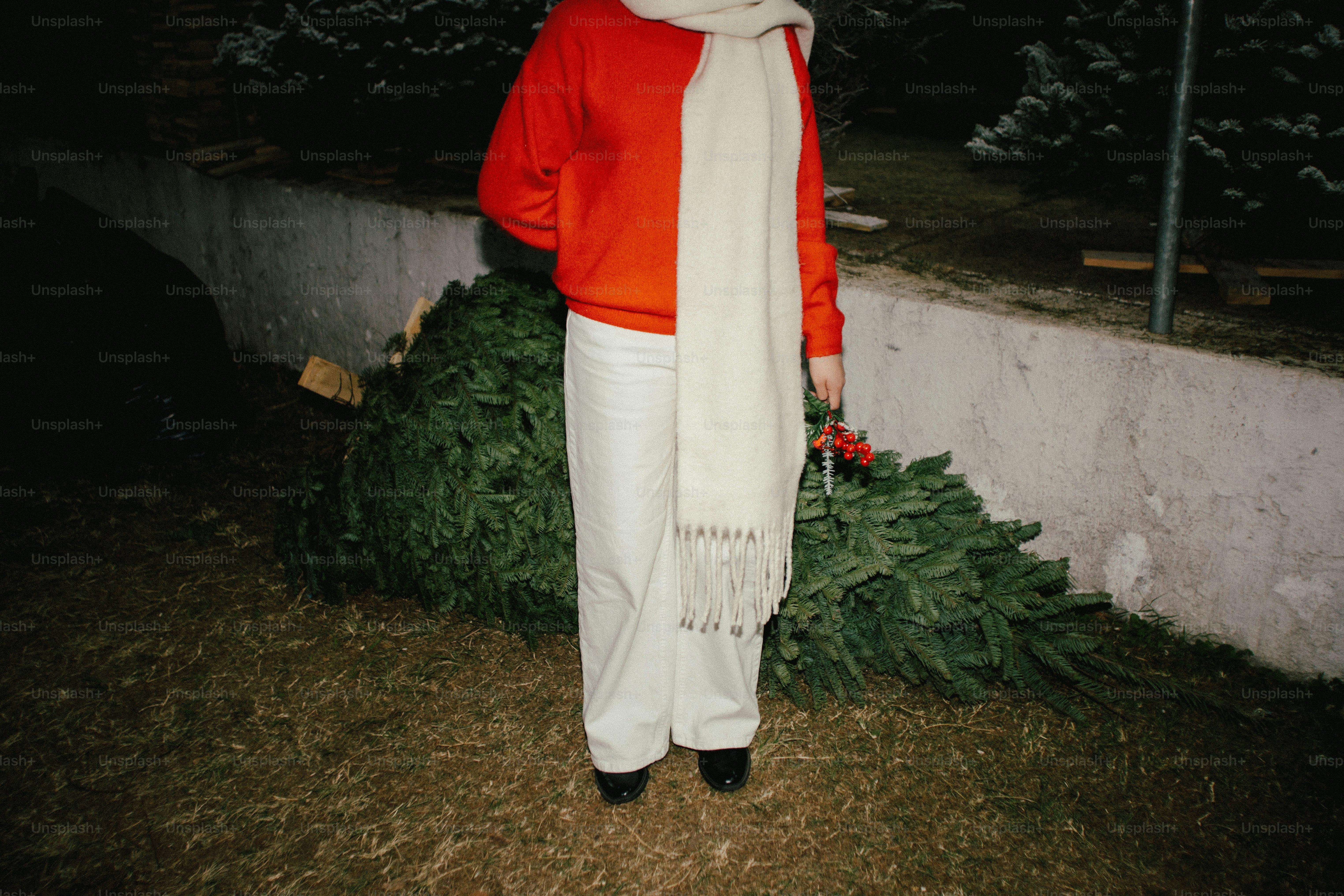 Persona con sudadera naranja y bufanda blanca con árbol de Navidad