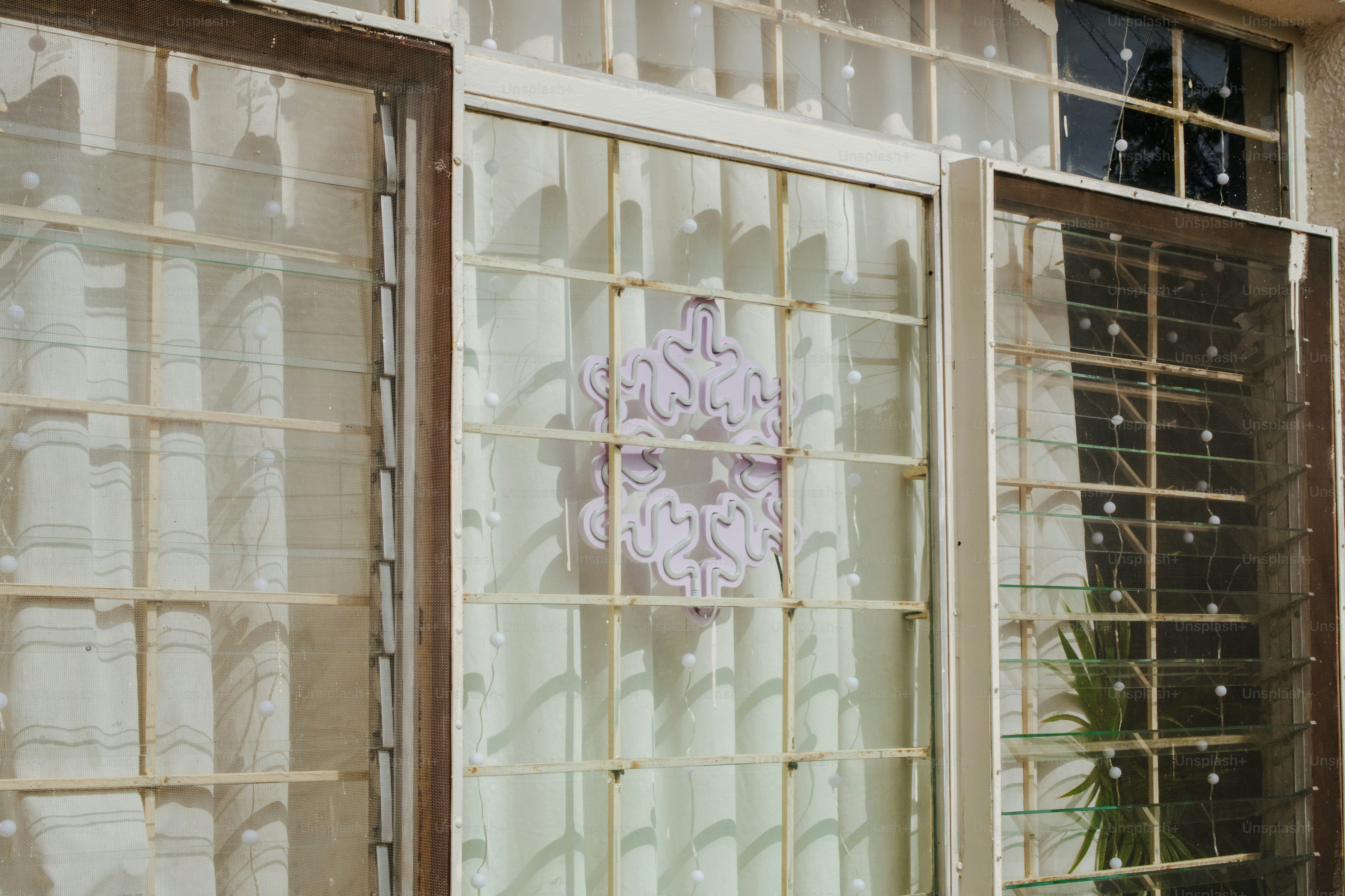 Three windows with metal security bars and curtains.