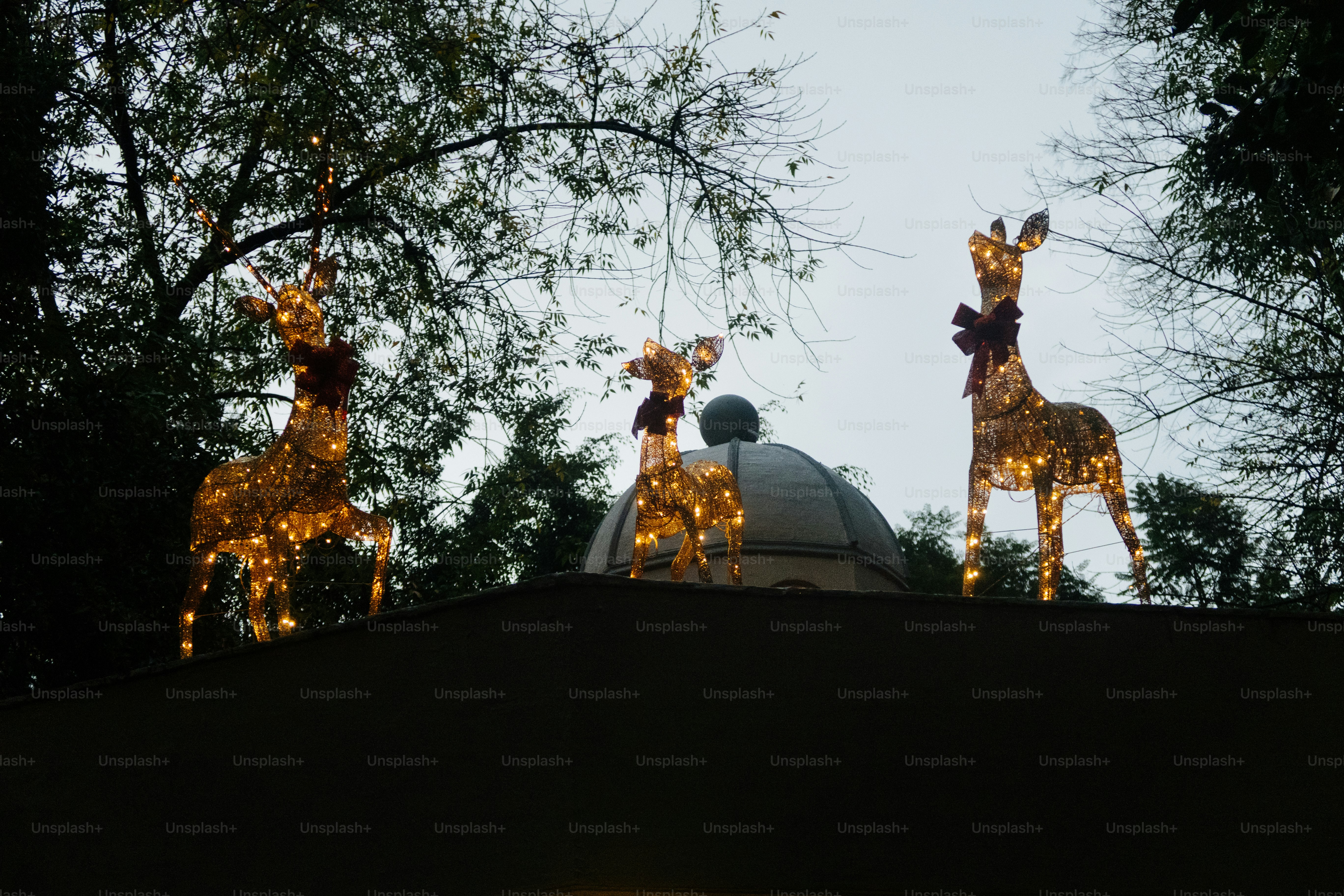 Three illuminated reindeer decorations on a rooftop.
