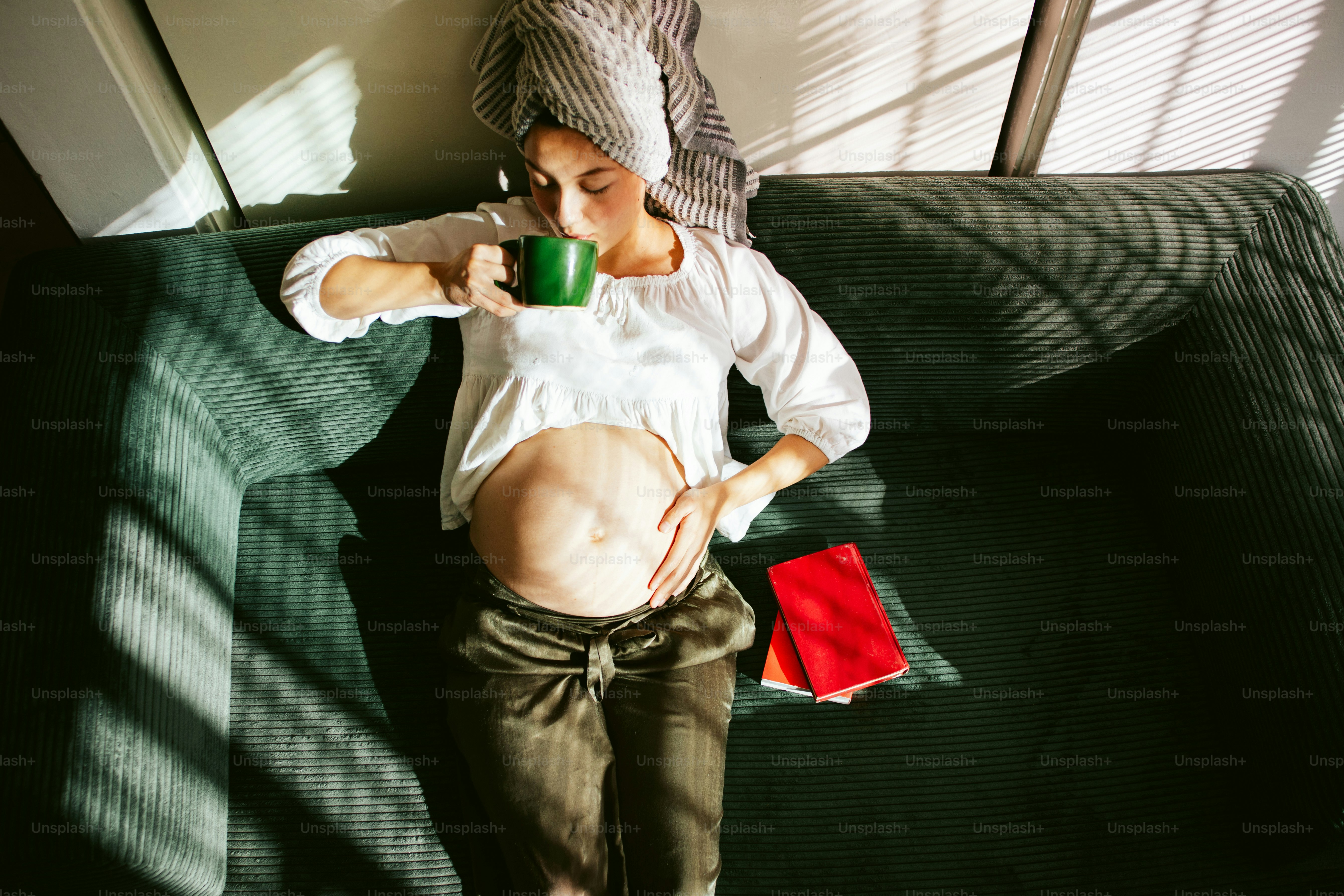 Pregnant woman relaxing on sofa with coffee.