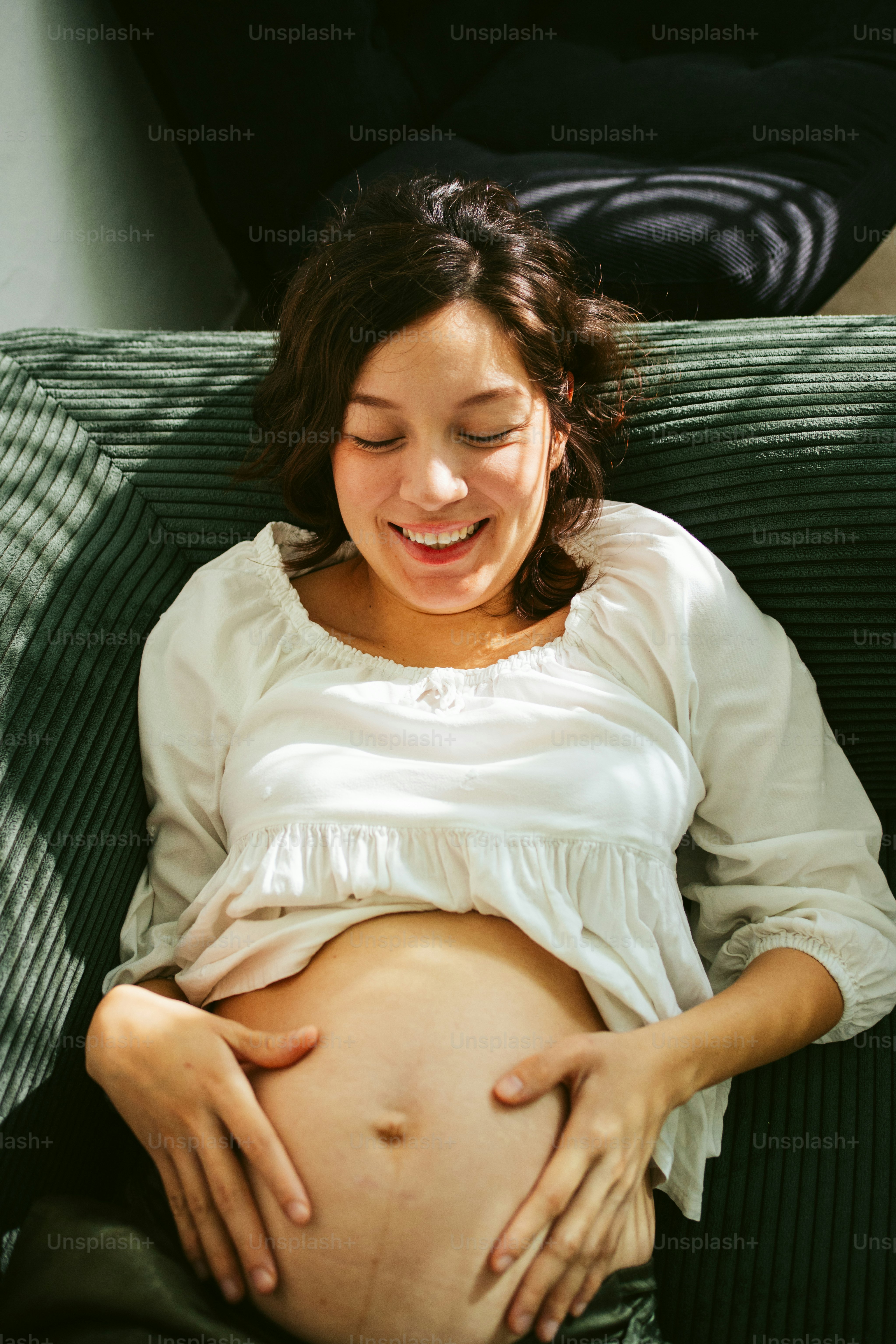 A smiling pregnant woman cradles her belly.