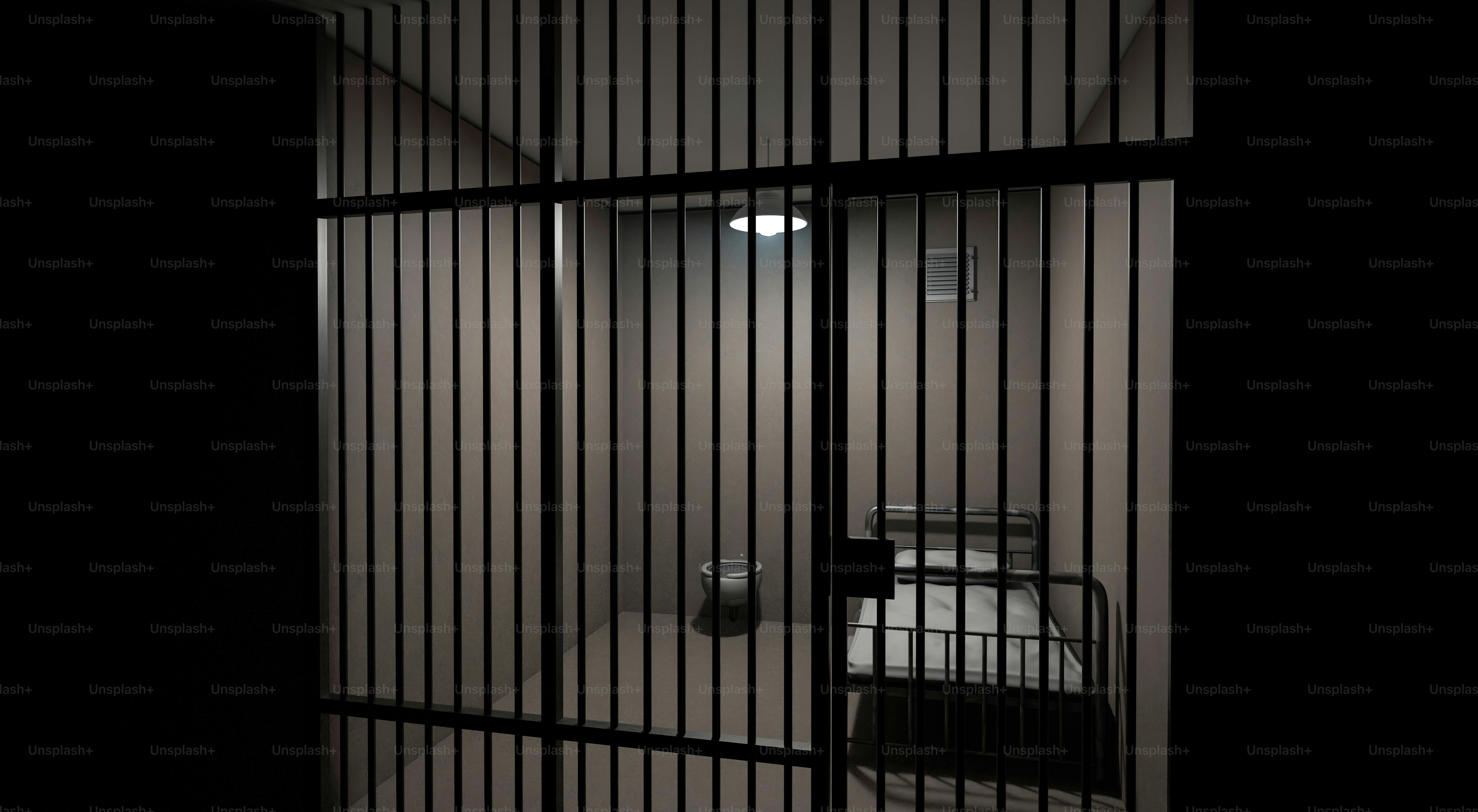 Empty jail cell with a bed and toilet.